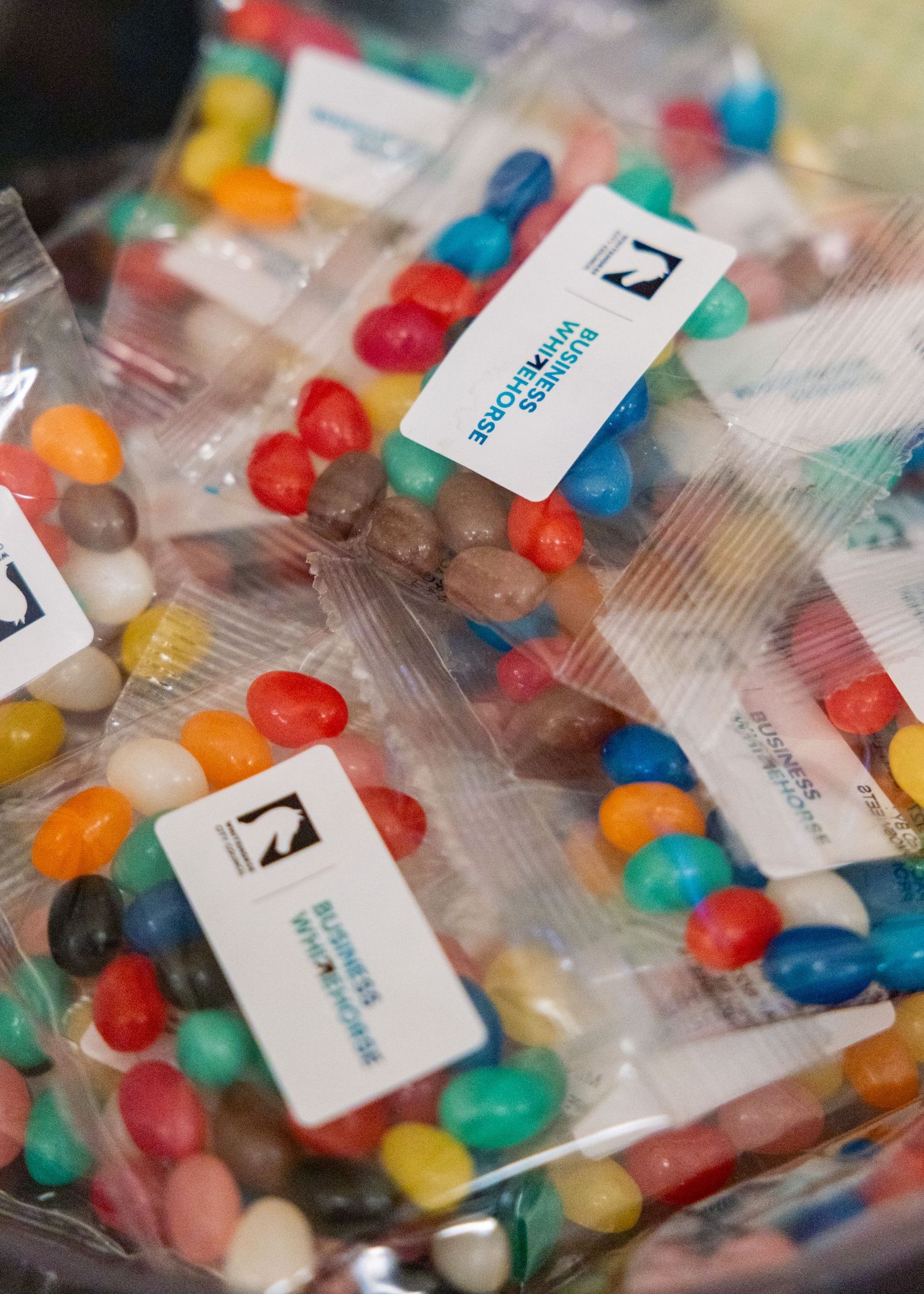 Colorful jelly bean bags with Whitehorse Business Group branding labels as event giveaways.