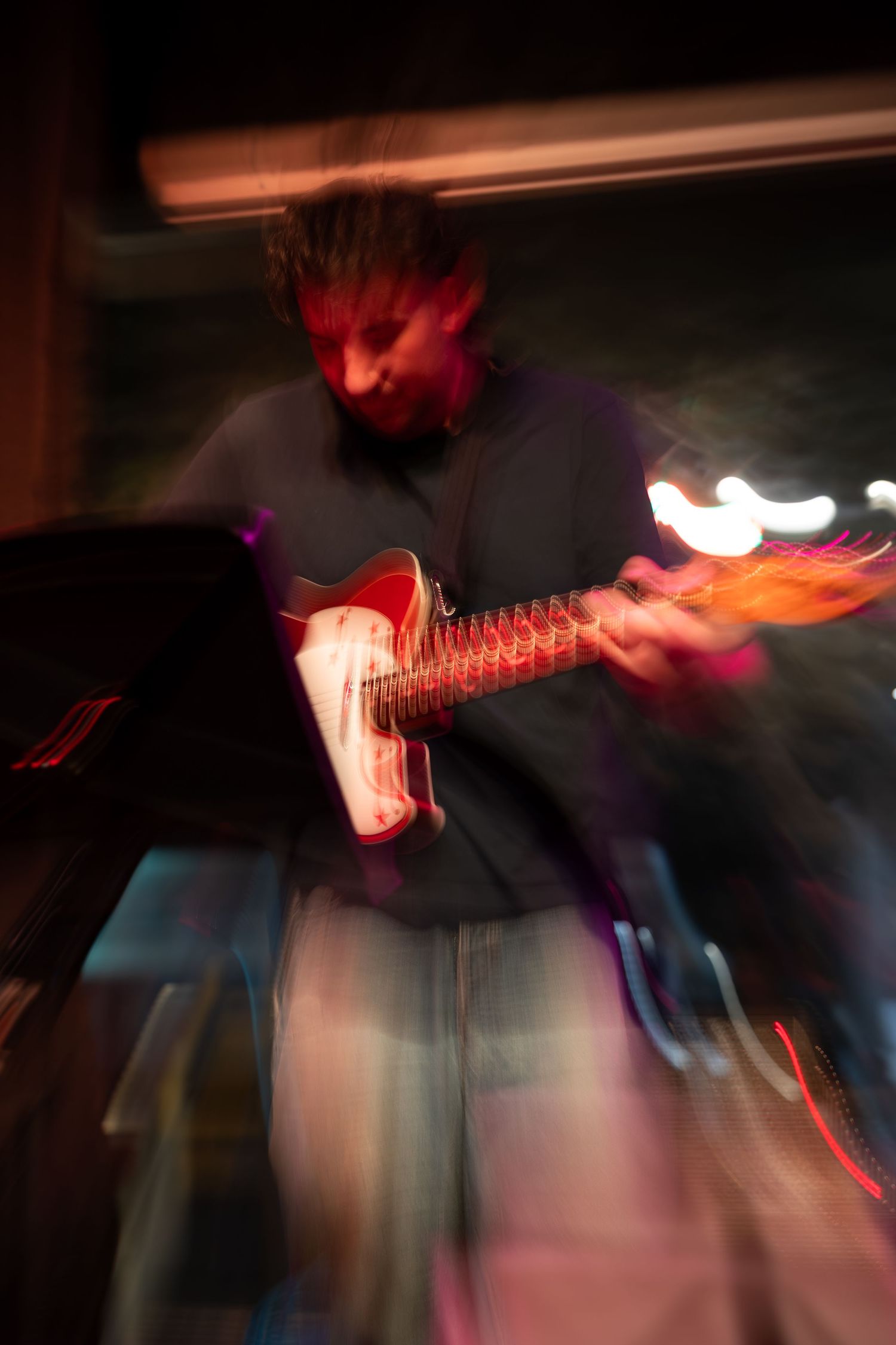 Motion-blurred guitarist performing on stage with dramatic lighting effects creating a dynamic live music atmosphere.