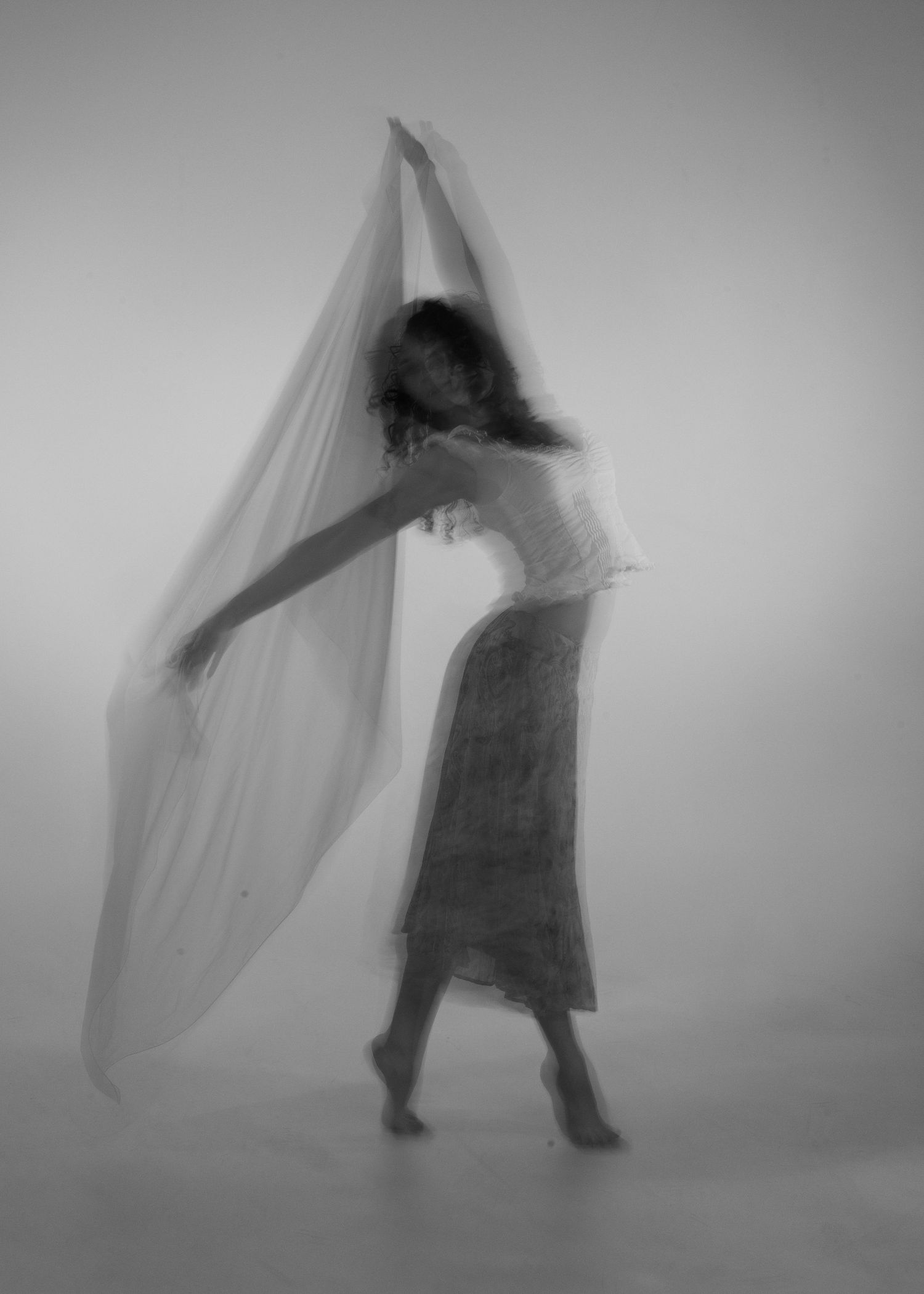 Dancer in motion with a sheer fabric veil in a dreamy black and white long exposure photograph.