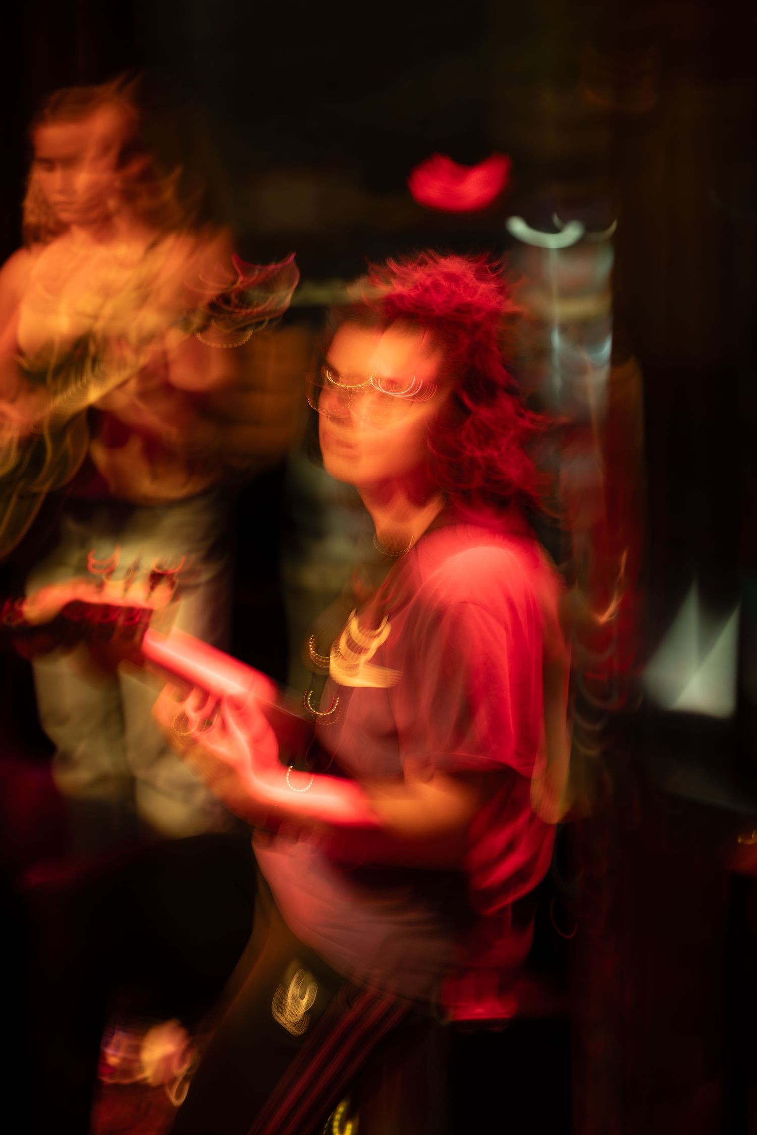 Motion-blurred performance in dark lighting with red stage illumination creates an atmospheric live music scene.