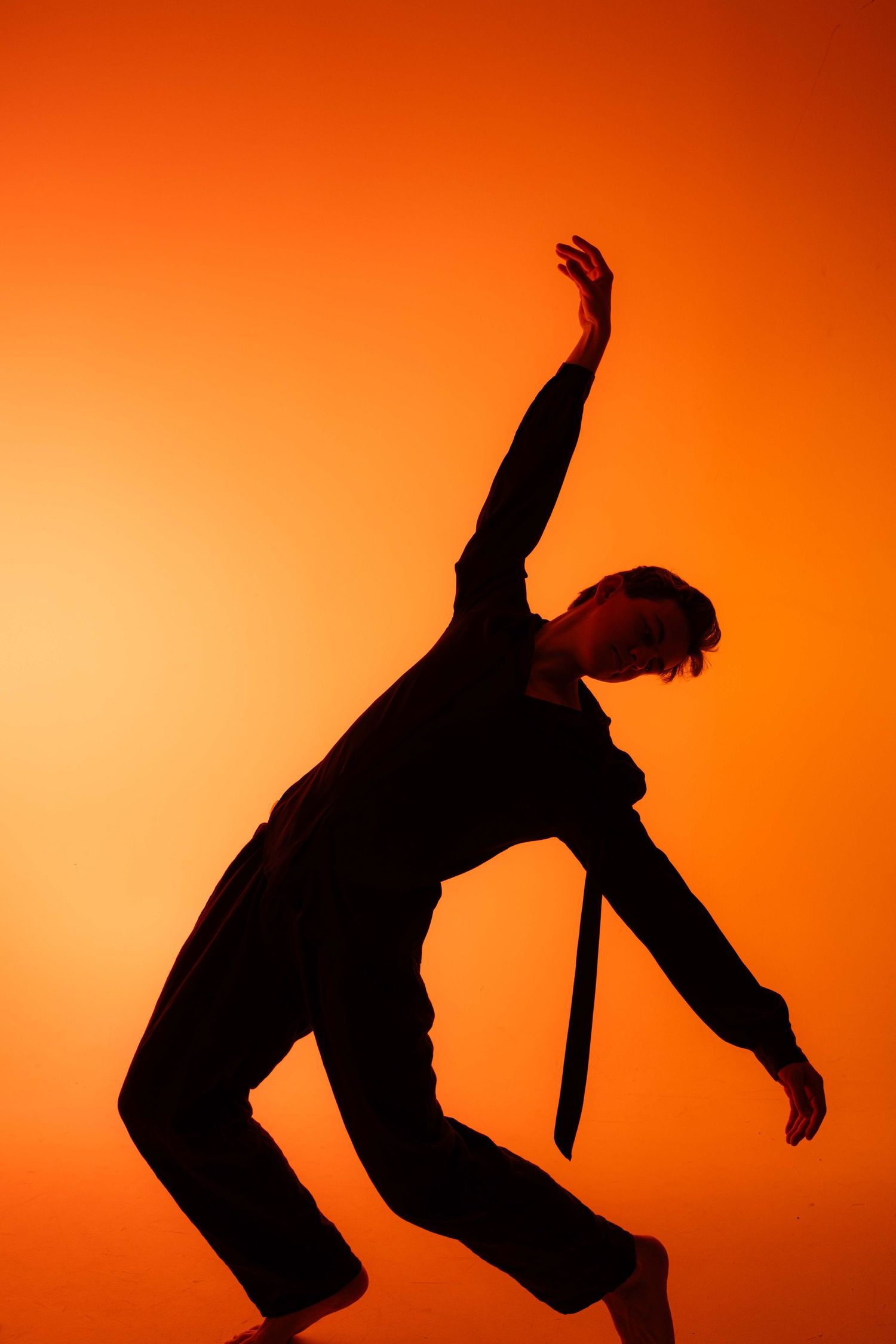 Silhouetted figure performs a dramatic backflip sequence against vibrant orange sunset background.