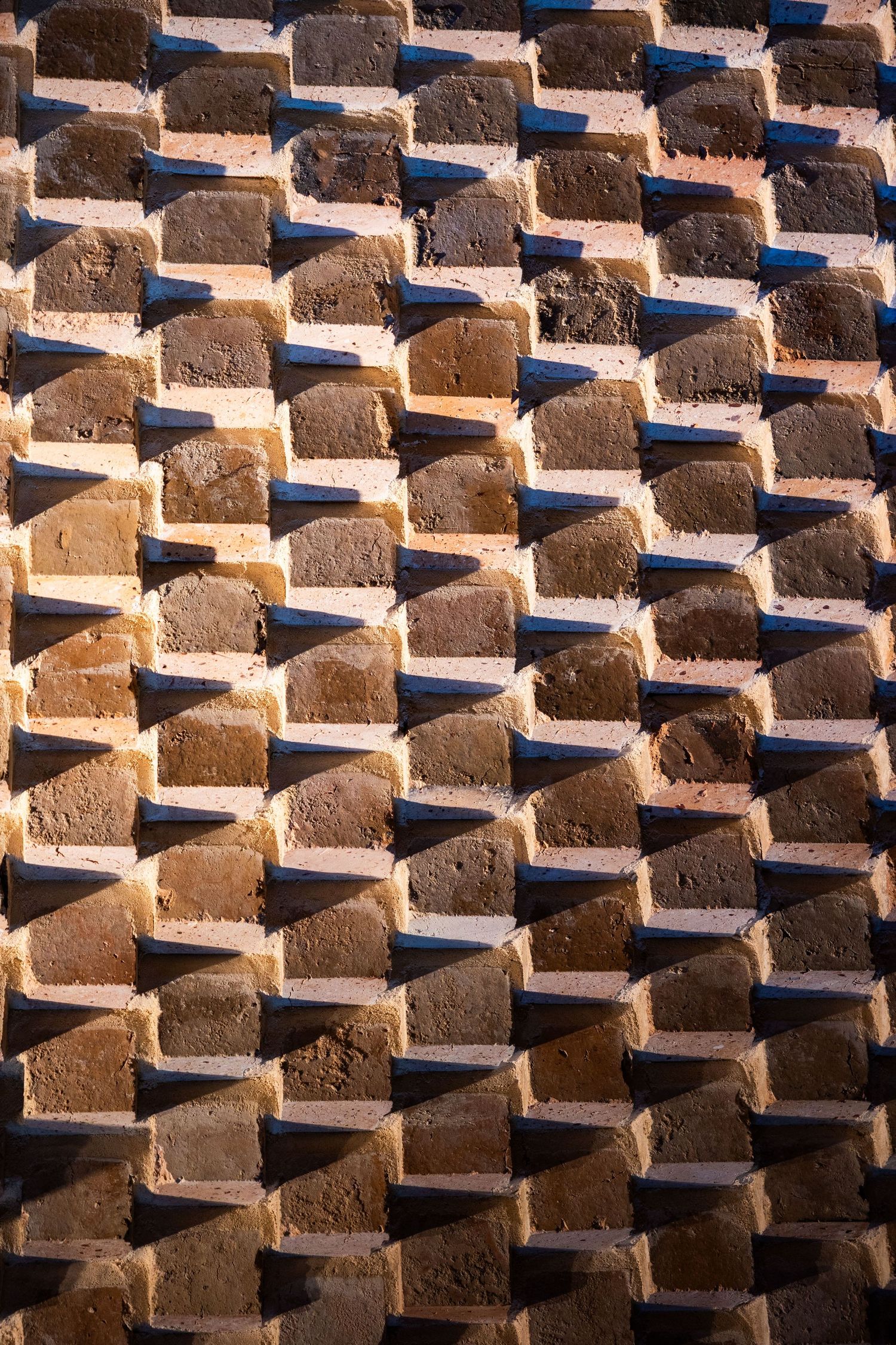 Close-up of a decorative brick wall with alternating brown and tan bricks arranged in a diagonal diamond pattern.