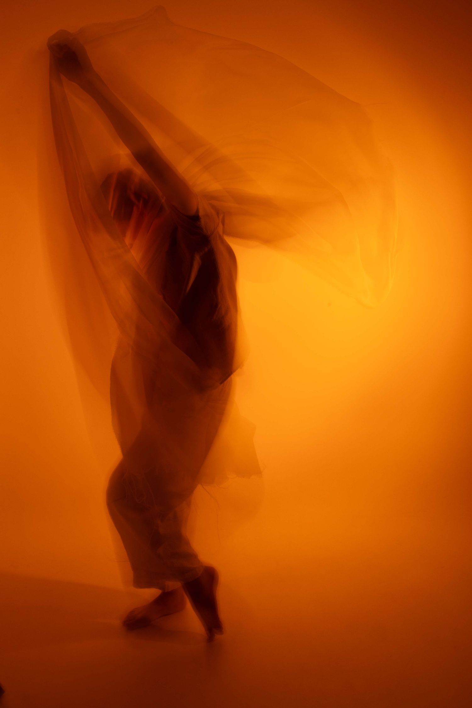 Flowing silhouettes of movement captured in a sequence against an orange-lit backdrop.