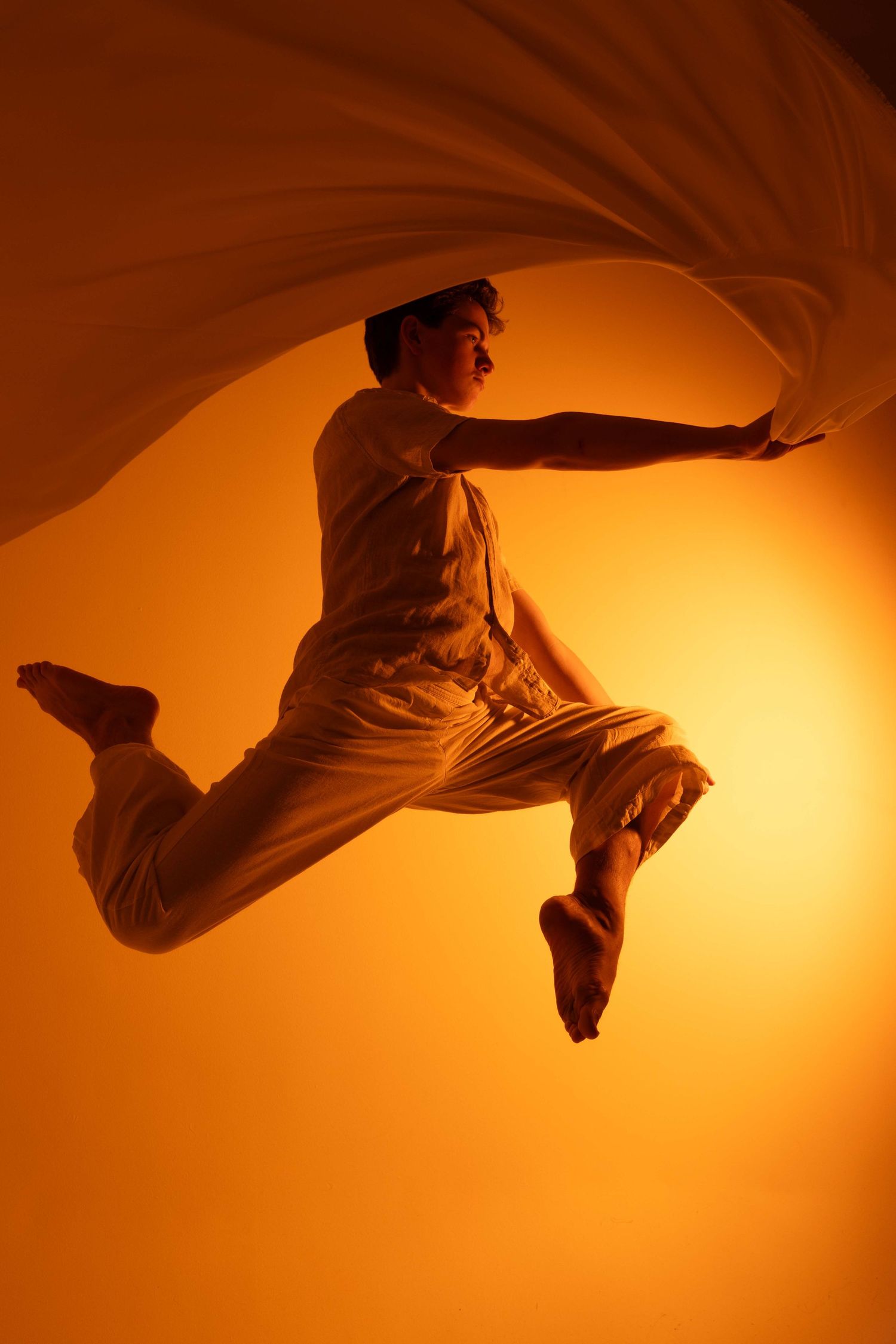Sequence of dancers performing aerial movements against a warm golden backdrop.