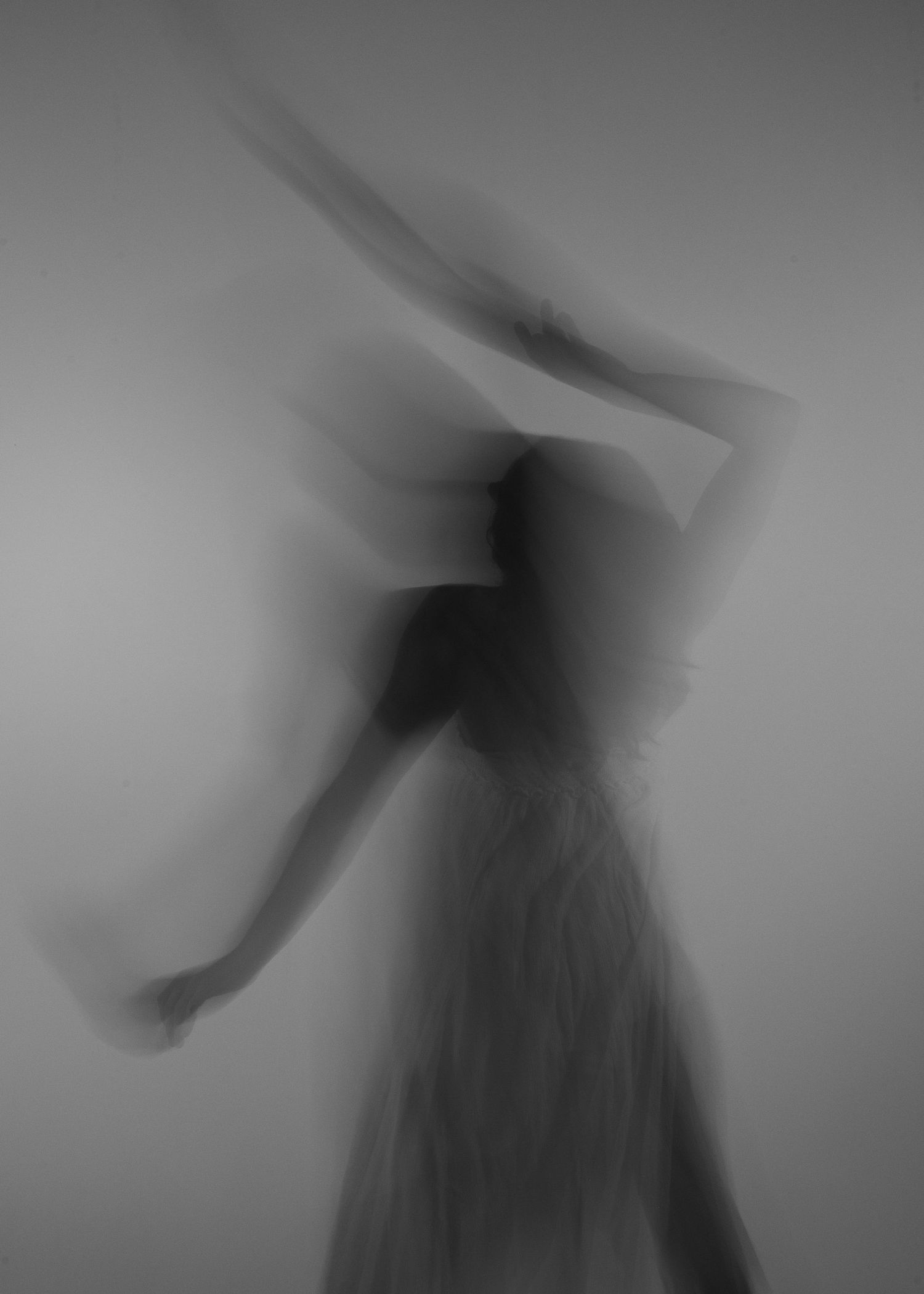 Blurred black and white long exposure photo of a dancer in motion wearing a flowing dress.