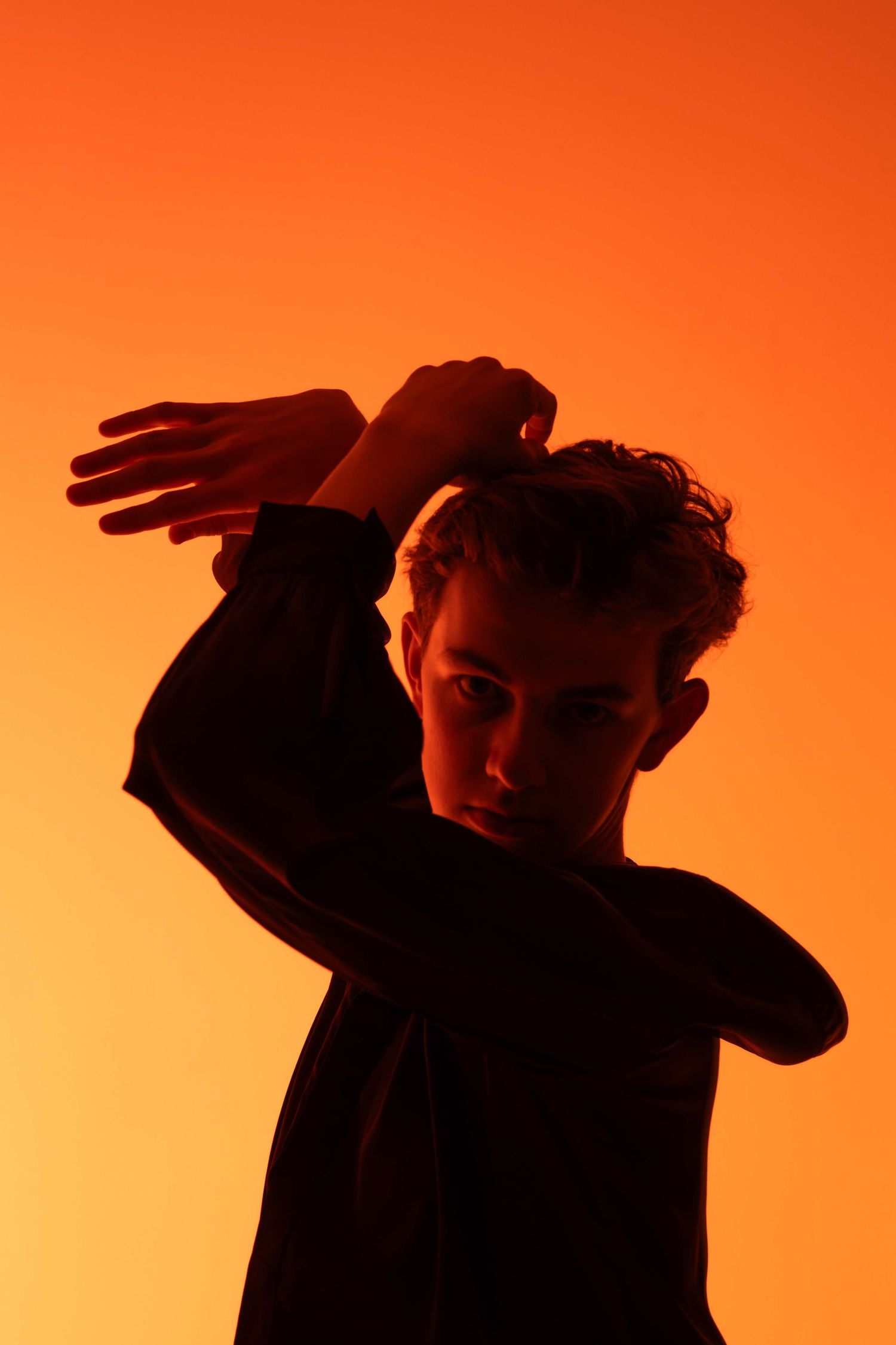 Dark silhouettes posed dramatically against a vibrant orange gradient background.