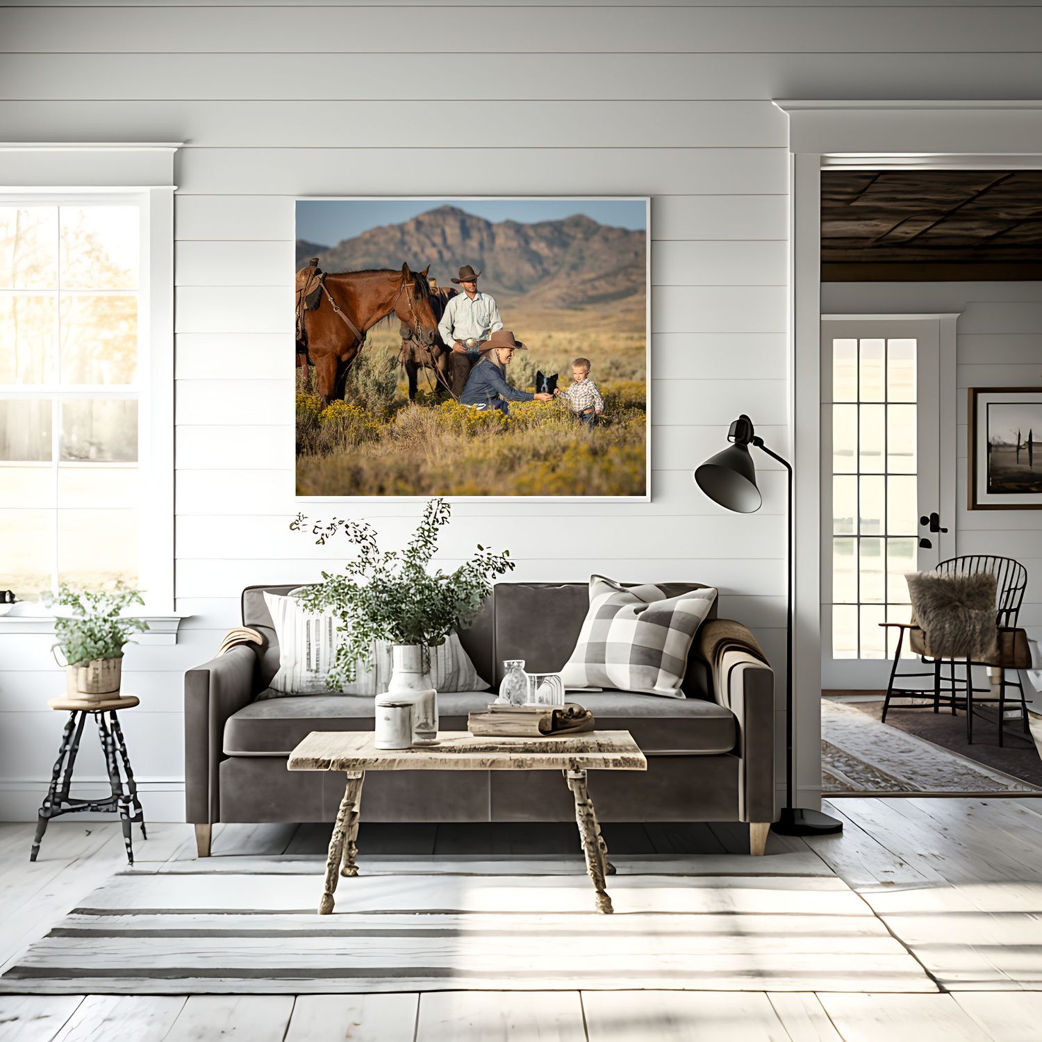 Cozy farmhouse living room with gray sofa, rustic coffee table, striped rug, and family western landscape canvas art above couch.