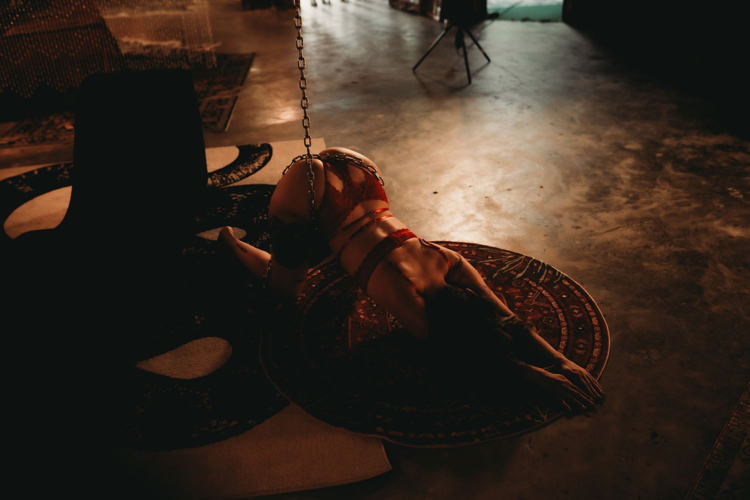 A person in ornate costume lying on a dimly lit floor beside decorative props in a dramatic scene.