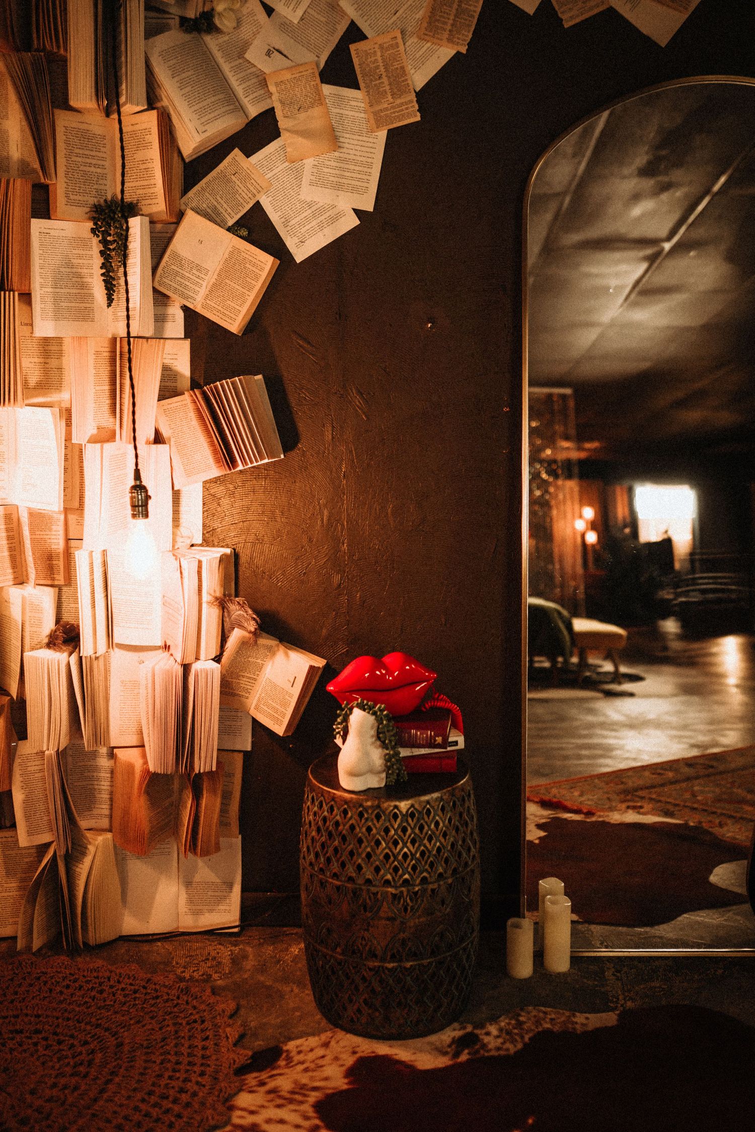 Books float magically against a dark wall with a red rose on a vintage barrel in a moody interior setting.