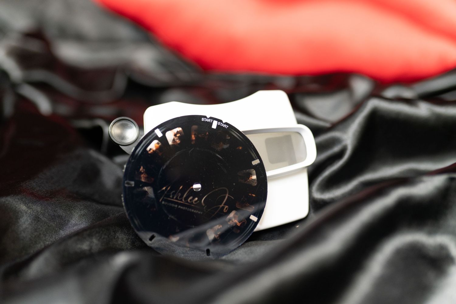 Close-up of vintage camera lens on black silk fabric with dramatic lighting.