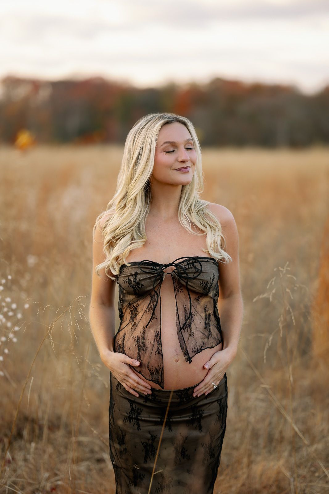 A pregnant woman in a black lace outfit cradles her belly during a maternity photoshoot in New Jersey.