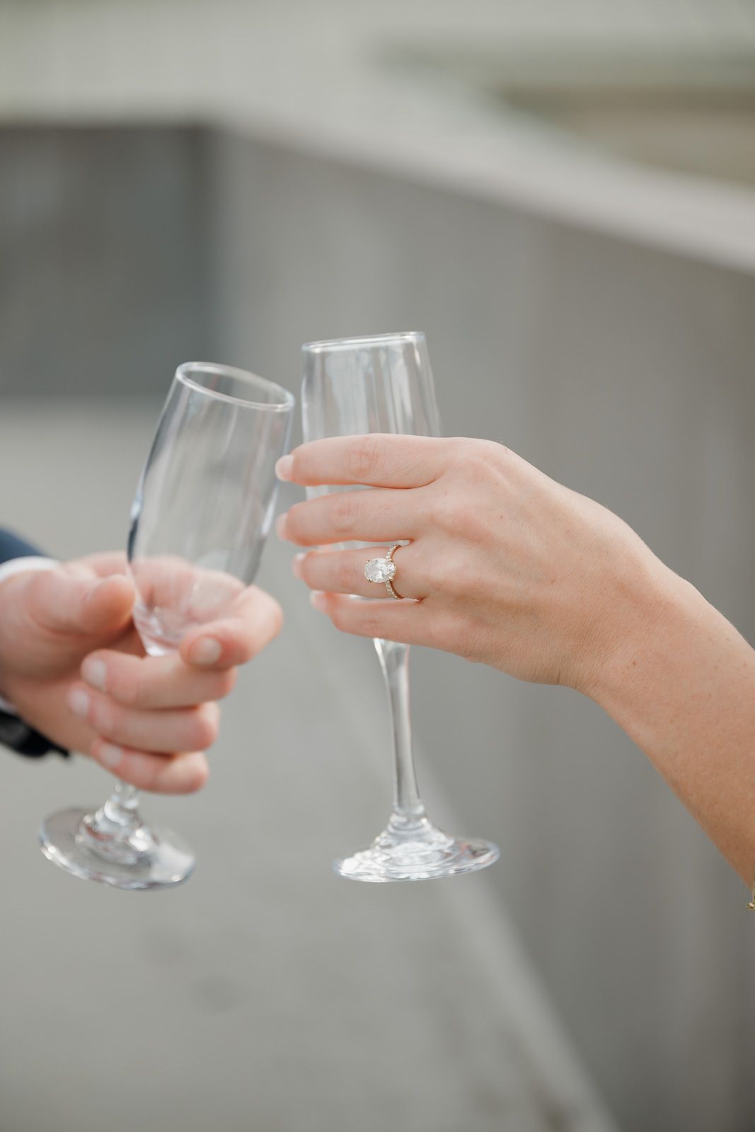 A sequence of hands holding empty wine glasses in a toasting motion against a blurred gray background.