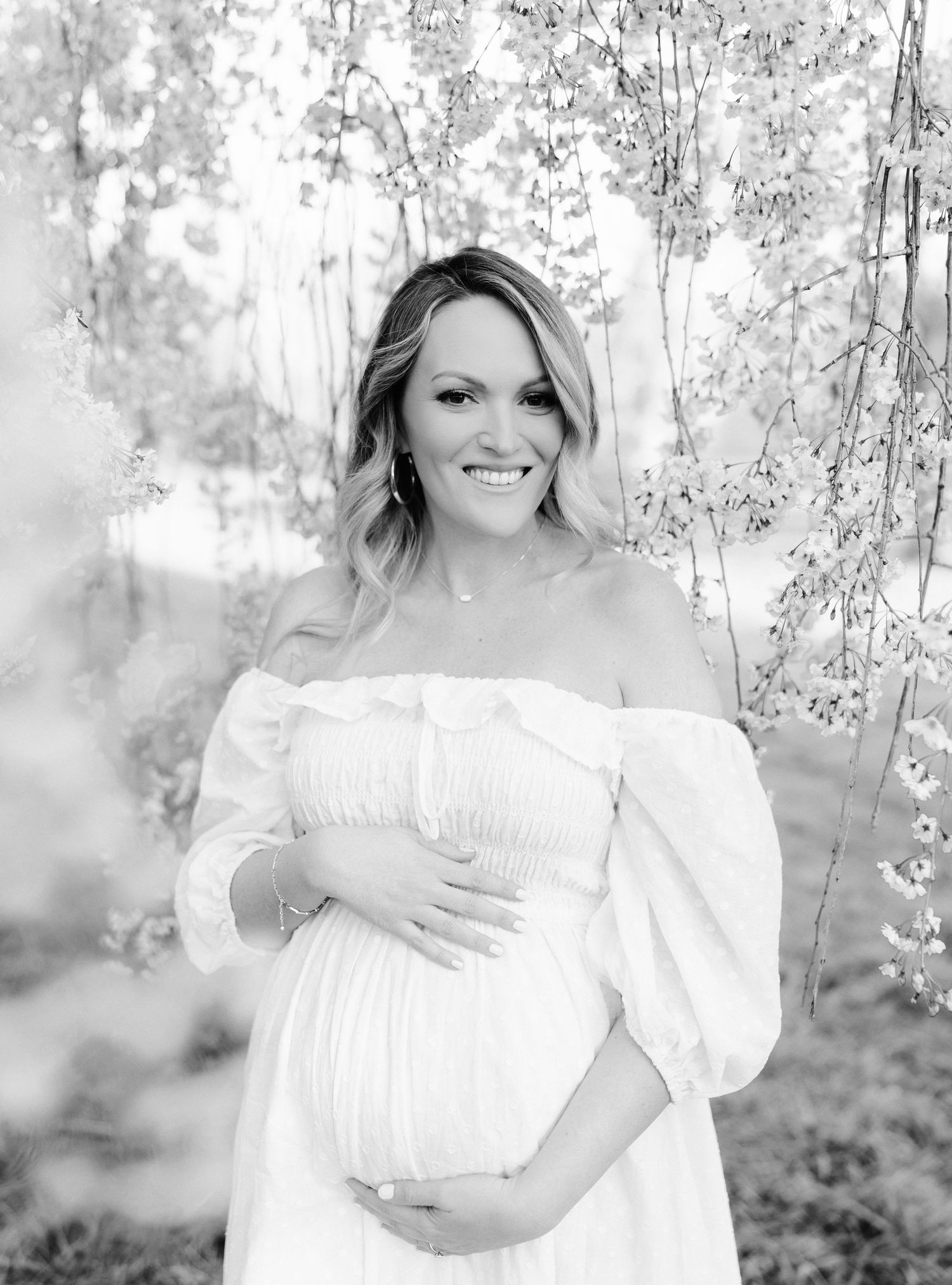 Ethereal maternity portraits in soft black and white against flowering trees.