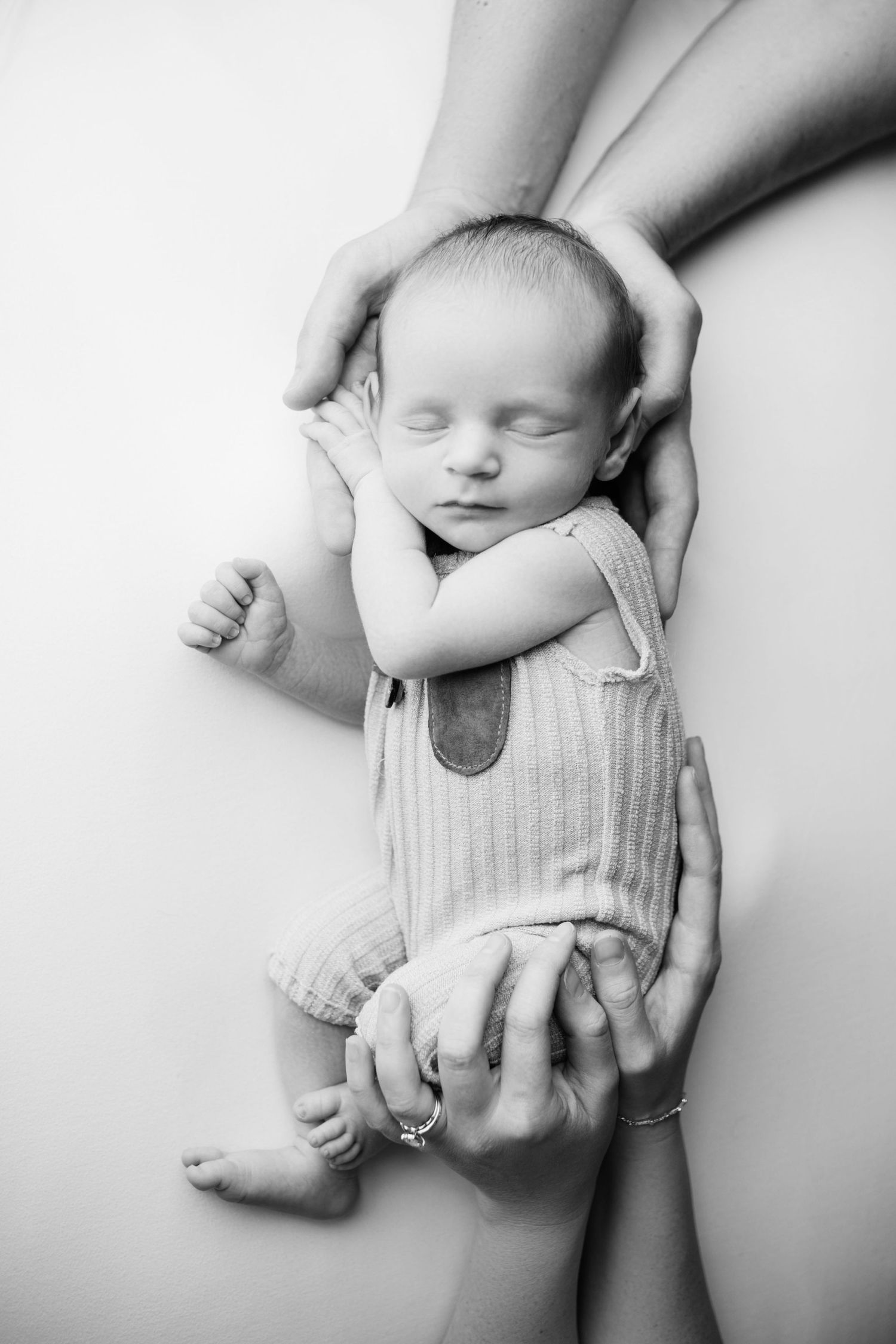 Black and white close-up photos of a newborn baby's tiny hands and feet against a soft white background.