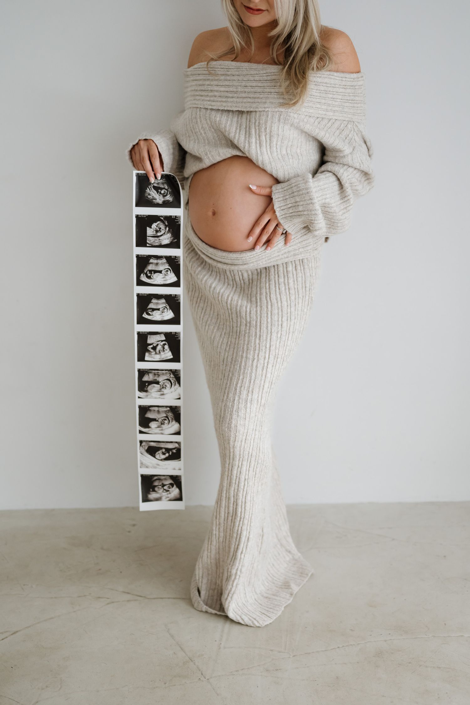 Pregnancy announcement photo showing off-shoulder cream sweater dress with ultrasound captured by a New Jersey maternity photographer