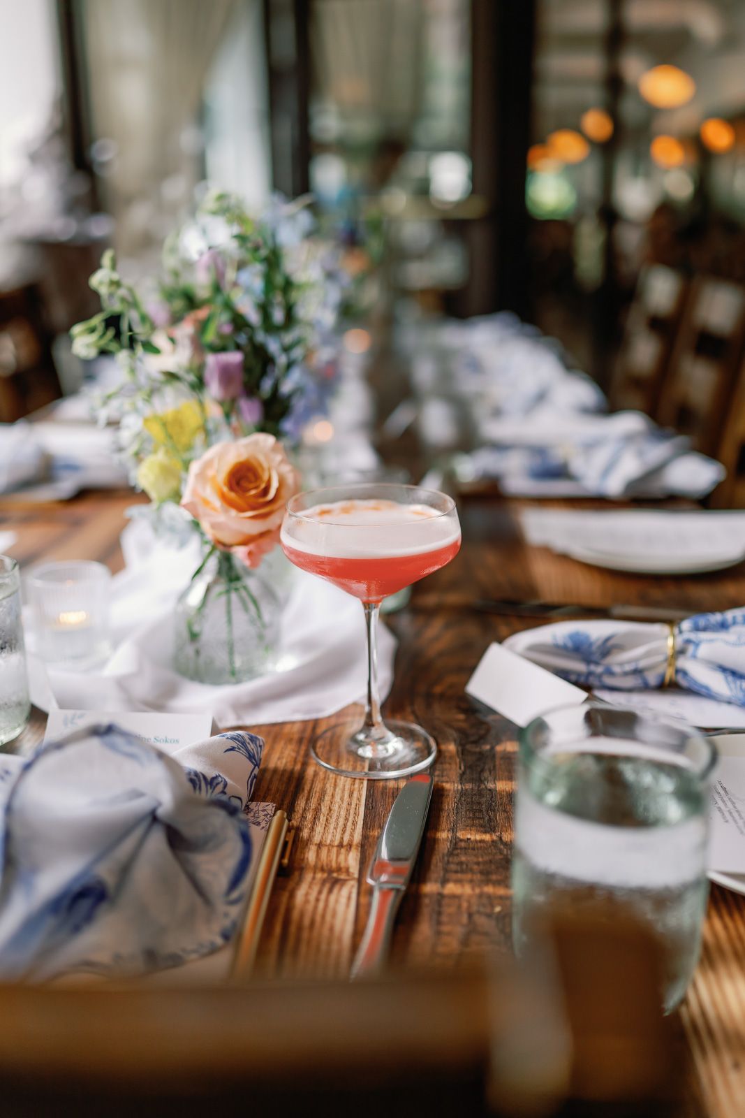Cocktail glasses and table settings on a rustic wooden surface in a restaurant setting photographed by a NJ event photographer.