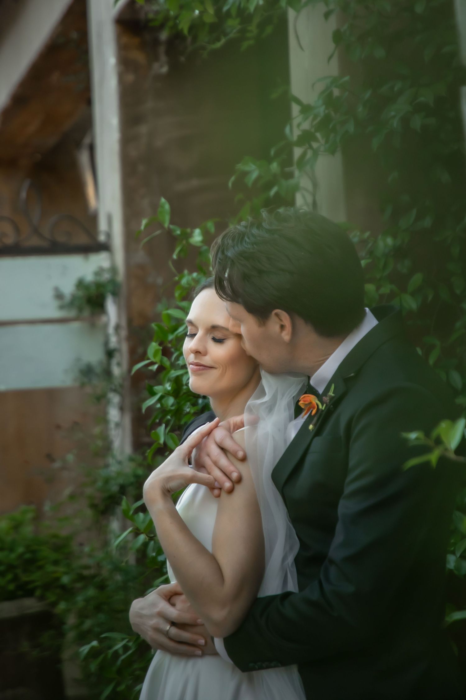 A romantic moment captured between newlyweds embracing in a garden setting during golden hour.