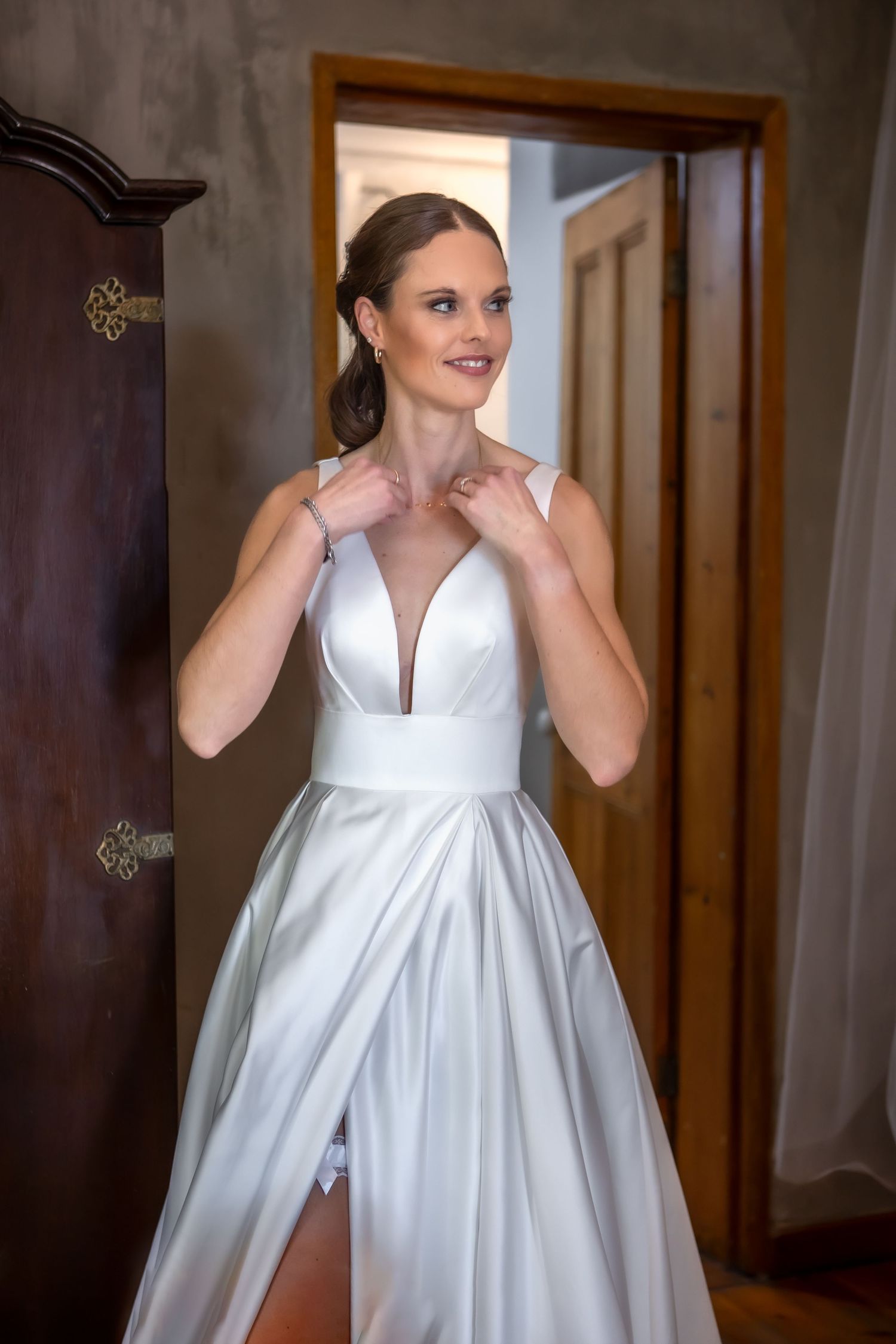 Elegant white wedding gown displayed in a rustic room with wooden doors.