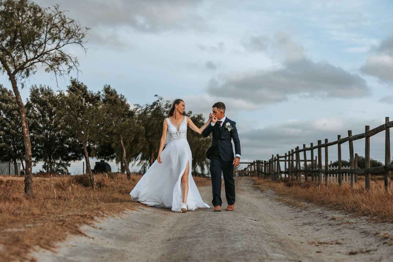 Wide landscape view of a wedding venue with rustic fencing and natural scenery.