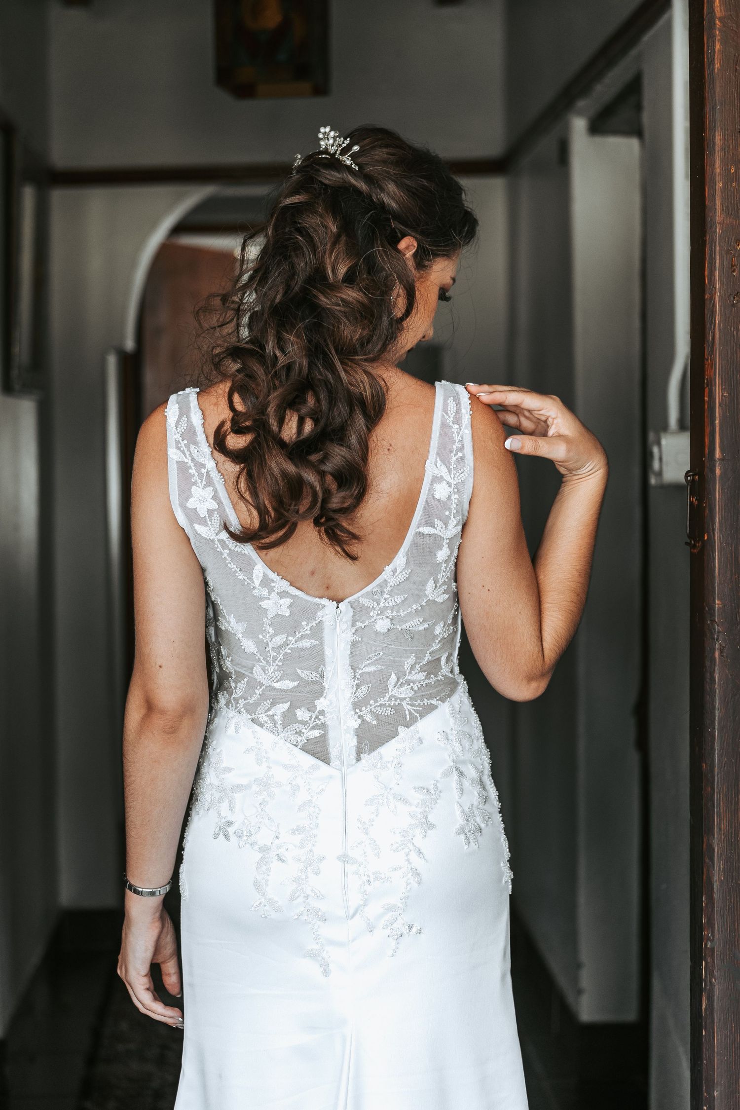 Back view of an intricate white wedding dress showing delicate lace details and button closures.