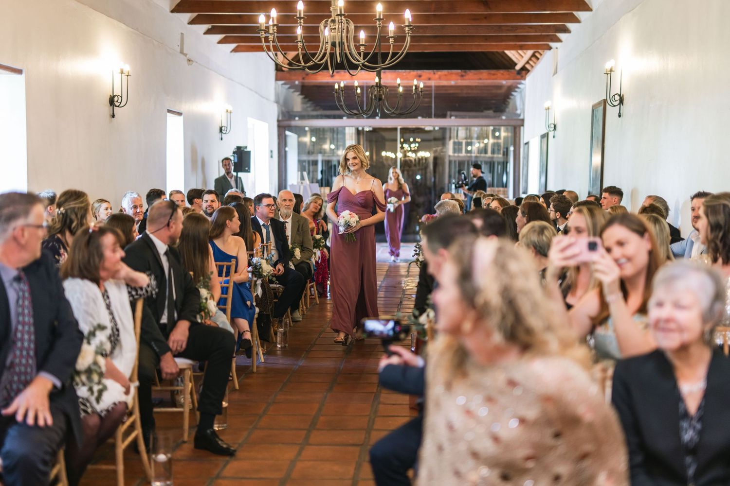 Wedding reception venue with exposed wooden beams and elegant chandeliers.
