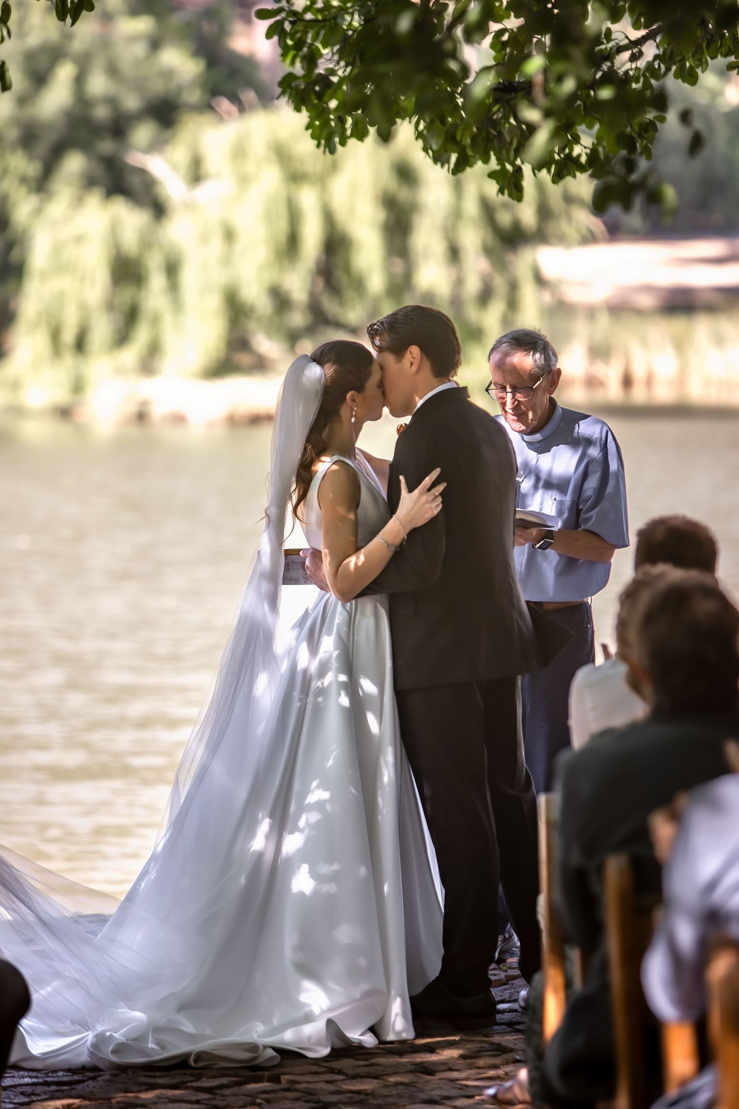 Intimate waterfront wedding ceremony with water and willow trees in background.