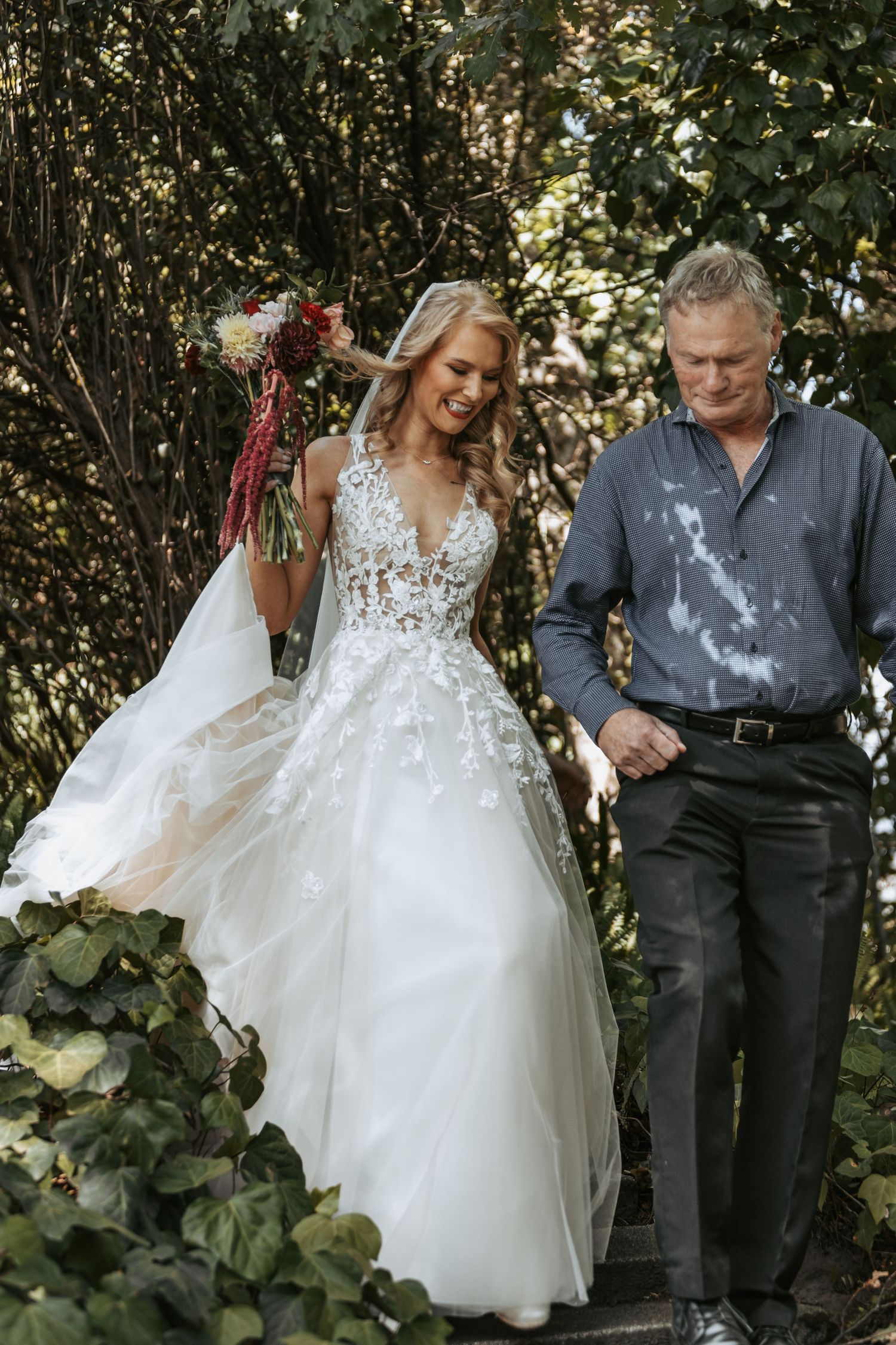 A tender moment between newlyweds in a garden setting with greenery and natural lighting.