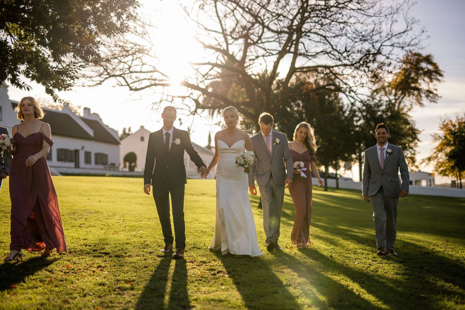 Wedding group silhouetted against dramatic sunset creates romantic outdoor portrait.