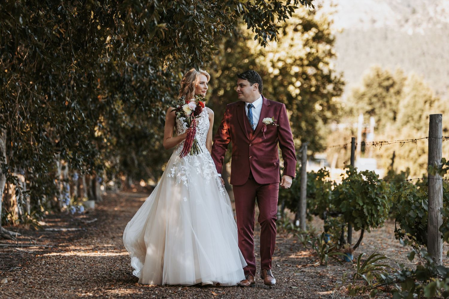 Wedding portraits captured in a tree-lined path with golden hour lighting.