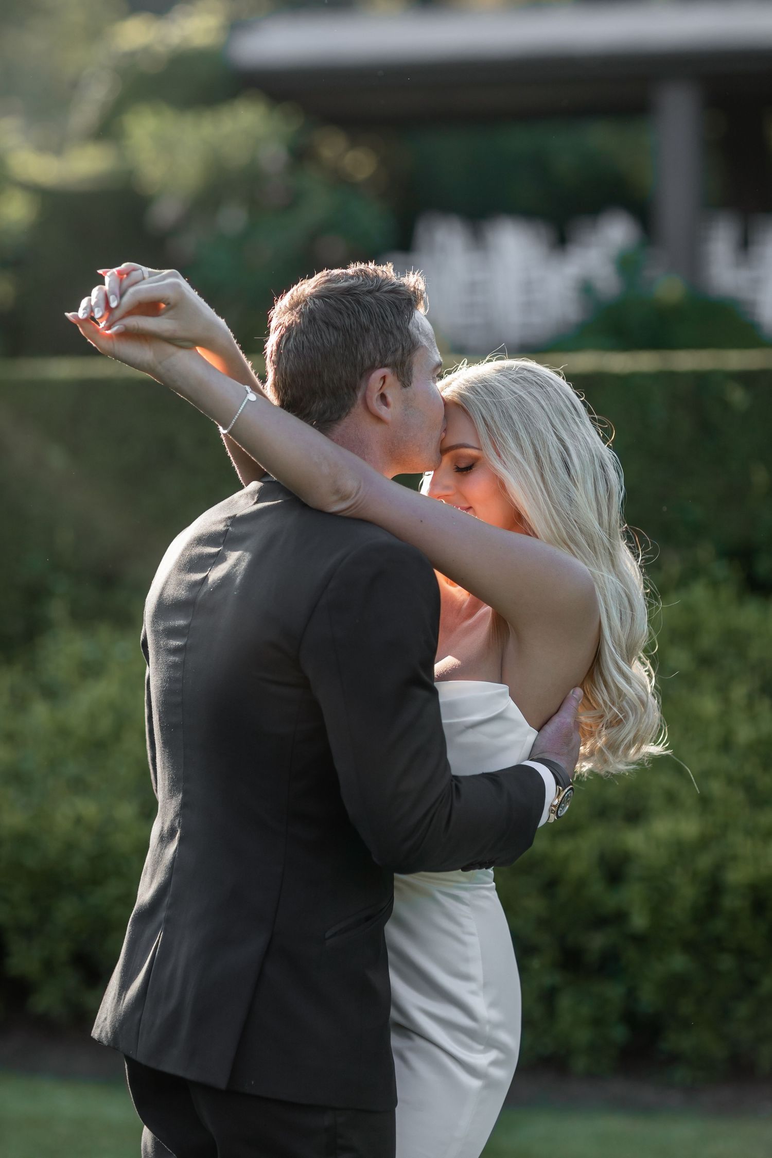 A romantic couple shares intimate kisses in a garden setting during golden hour, captured in a sequence of photos.