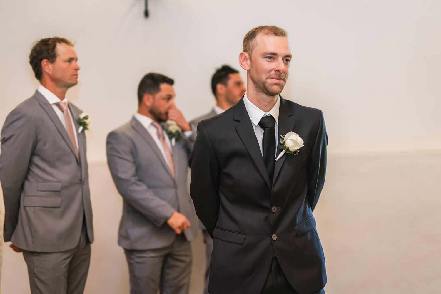 Wedding party members in gray and black suits gather before the ceremony.