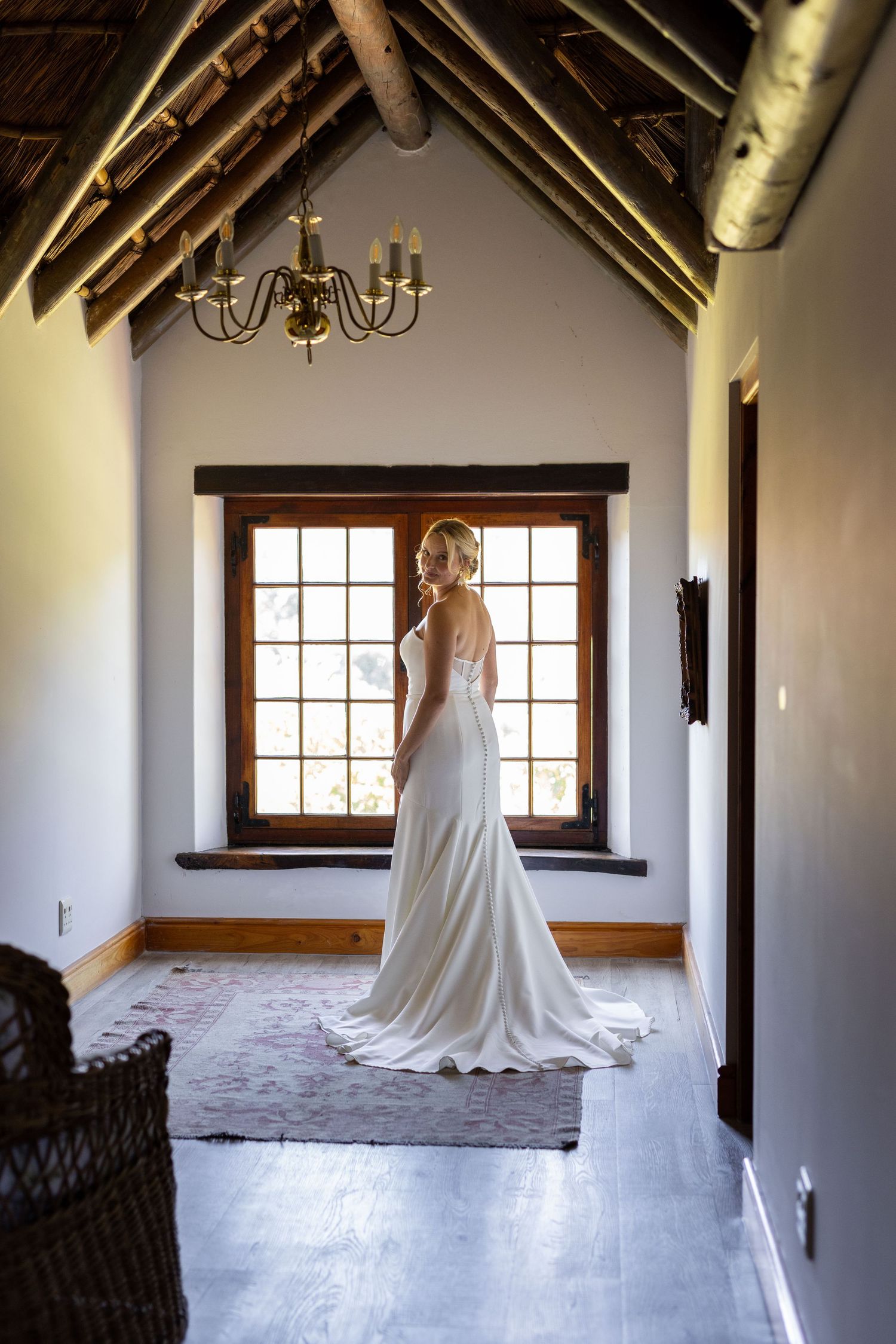 A series of elegant bridal portraits showing a white wedding dress in a rustic room with wooden beams and windows.