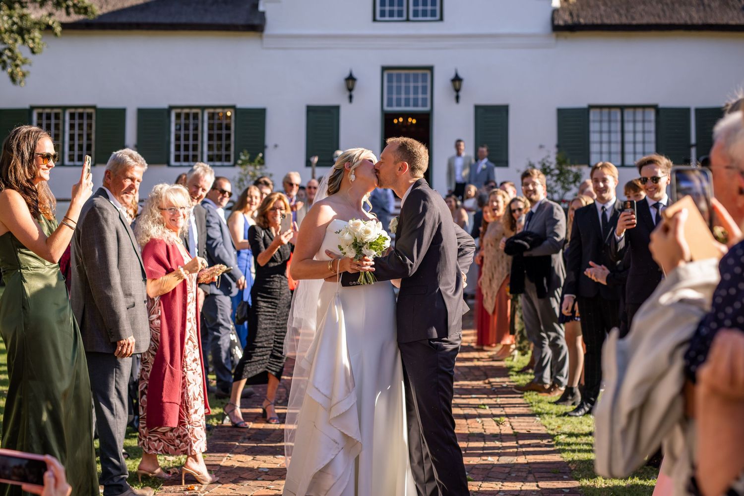 Guests form two lines outside a historic white building during a wedding reception.