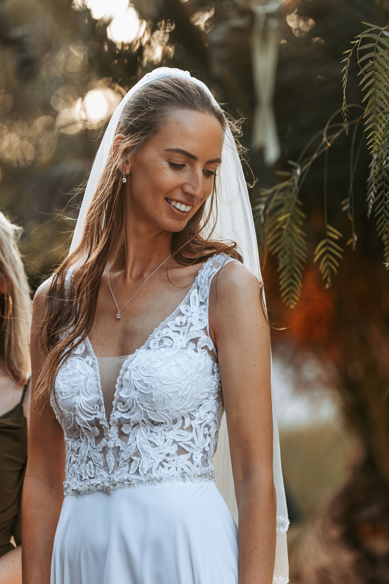 Close-up details of a delicate white lace wedding dress with intricate patterns in natural lighting.