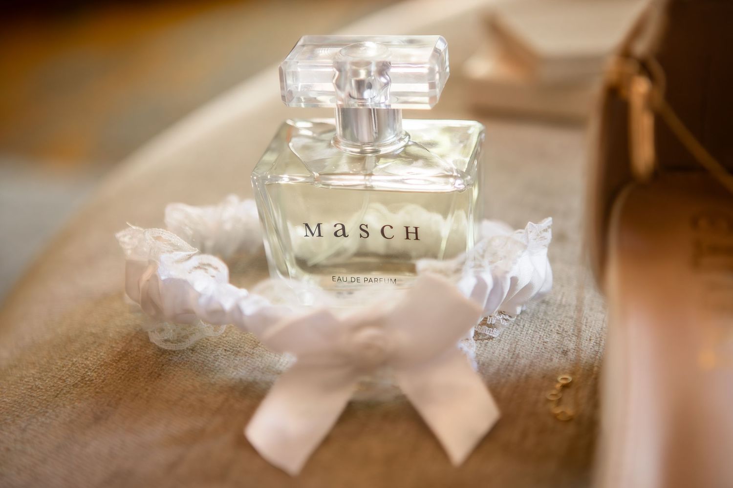 Elegant perfume bottles and wedding accessories arranged on a reflective surface with soft lighting.