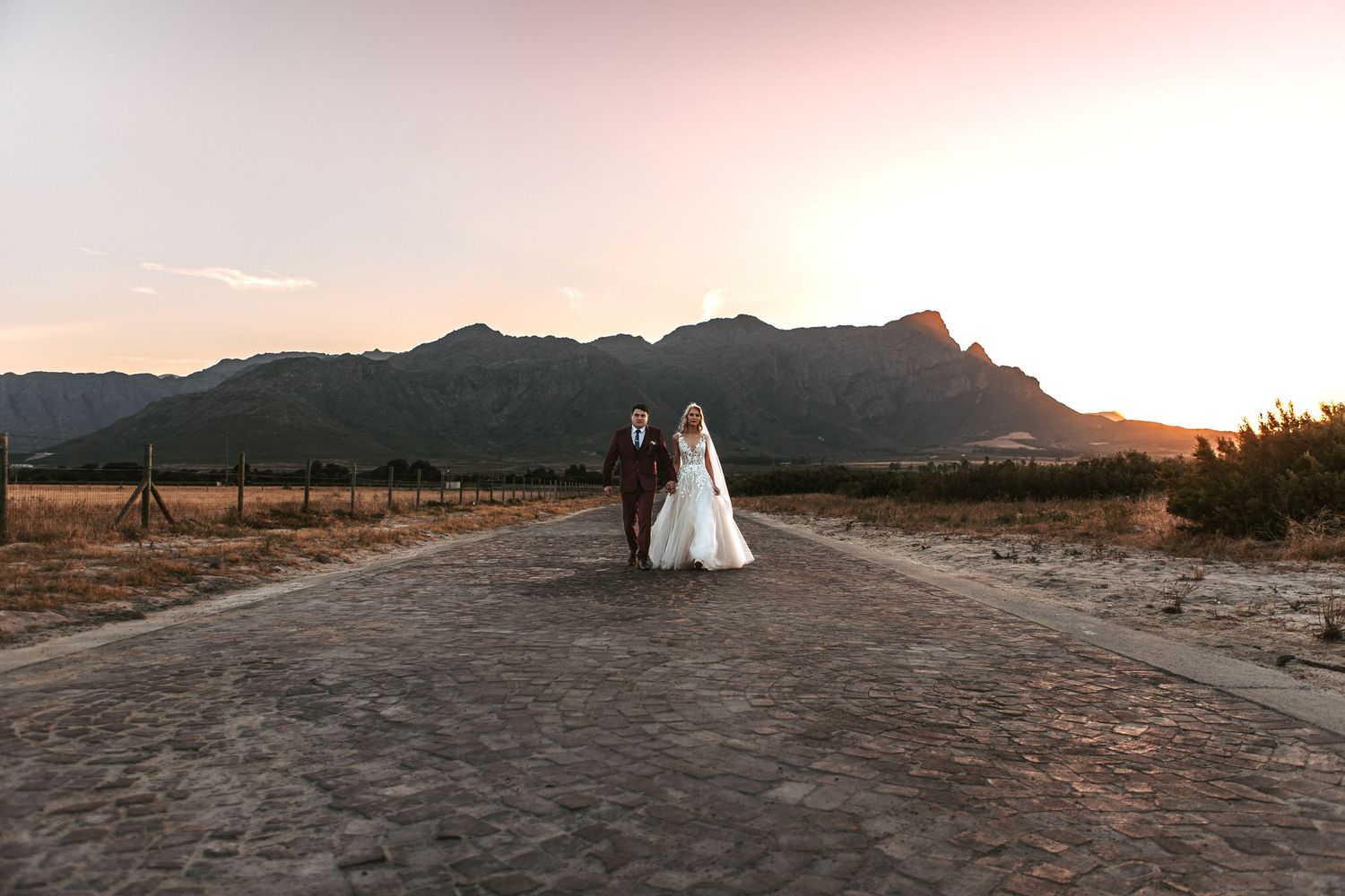 A wide landscape shot of a wedding couple in a desert setting during sunset.