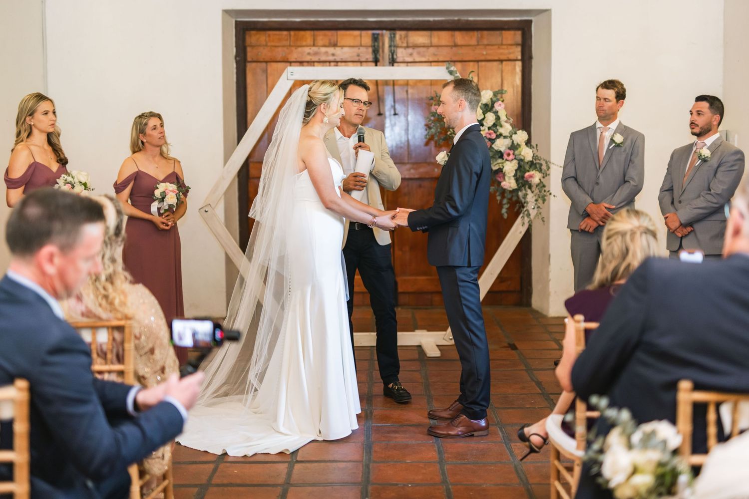 Indoor wedding ceremony at an elegant venue with guests seated in rows.