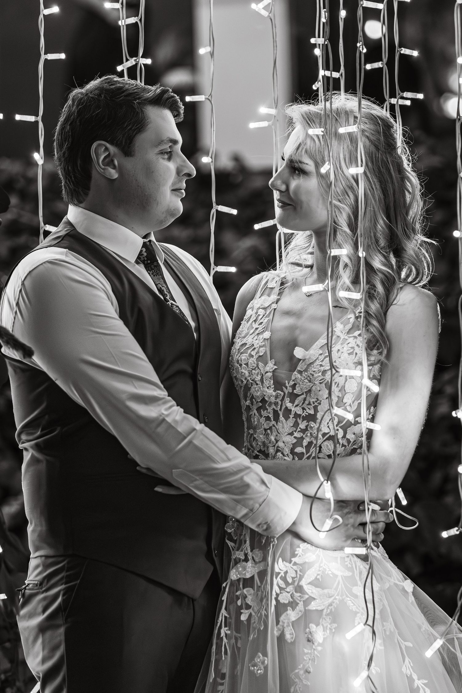 A romantic slow dance moment at a wedding reception with soft lighting and hanging decorations.