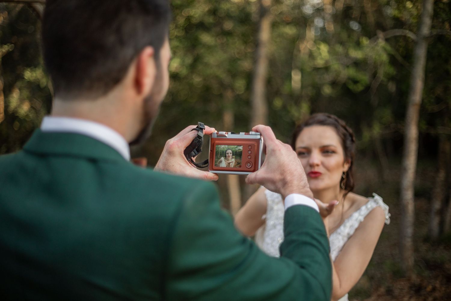 Wedding couple playfully poses in front of greenery during outdoor photo session.