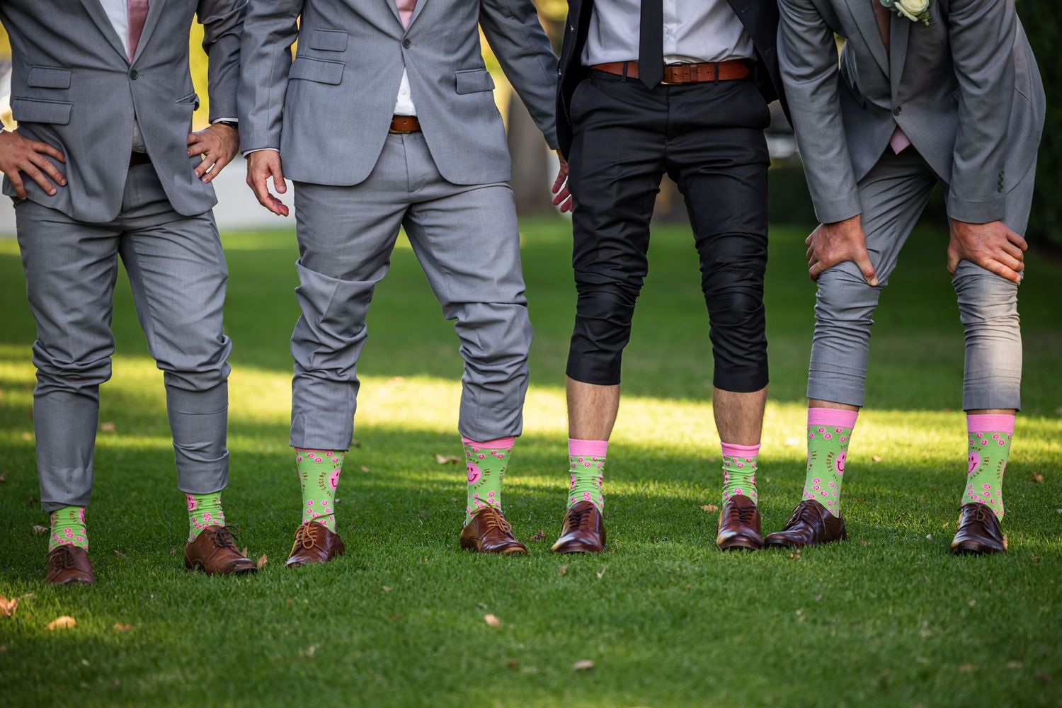 Fun wedding party photo showing groomsmen's matching gray suits and brown shoes.