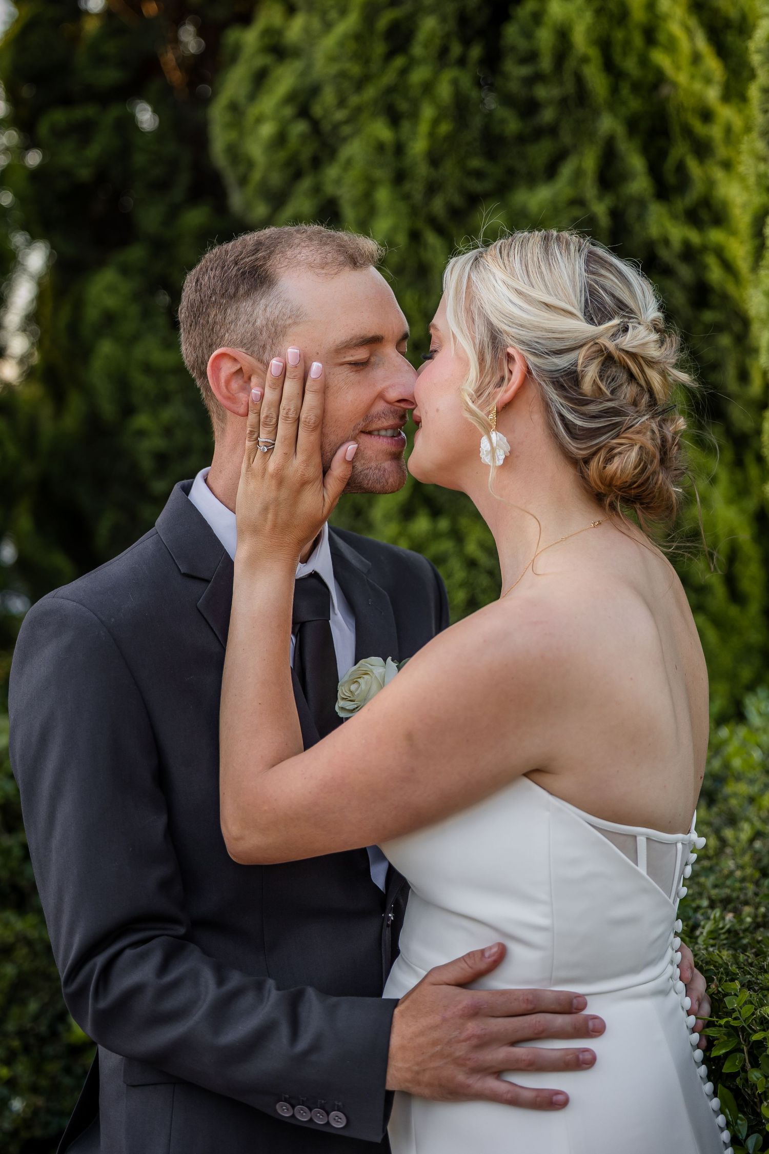 Romantic sequence of newlyweds sharing their first kiss as a married couple in a garden setting.