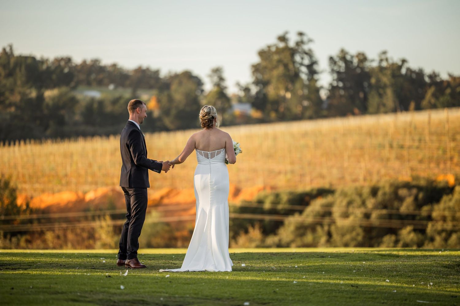 Couple poses together in a golden sunlit field during their wedding photoshoot.