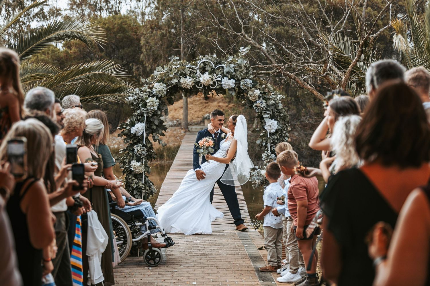 Wedding guests line pathway to celebrate newlyweds during outdoor ceremony.
