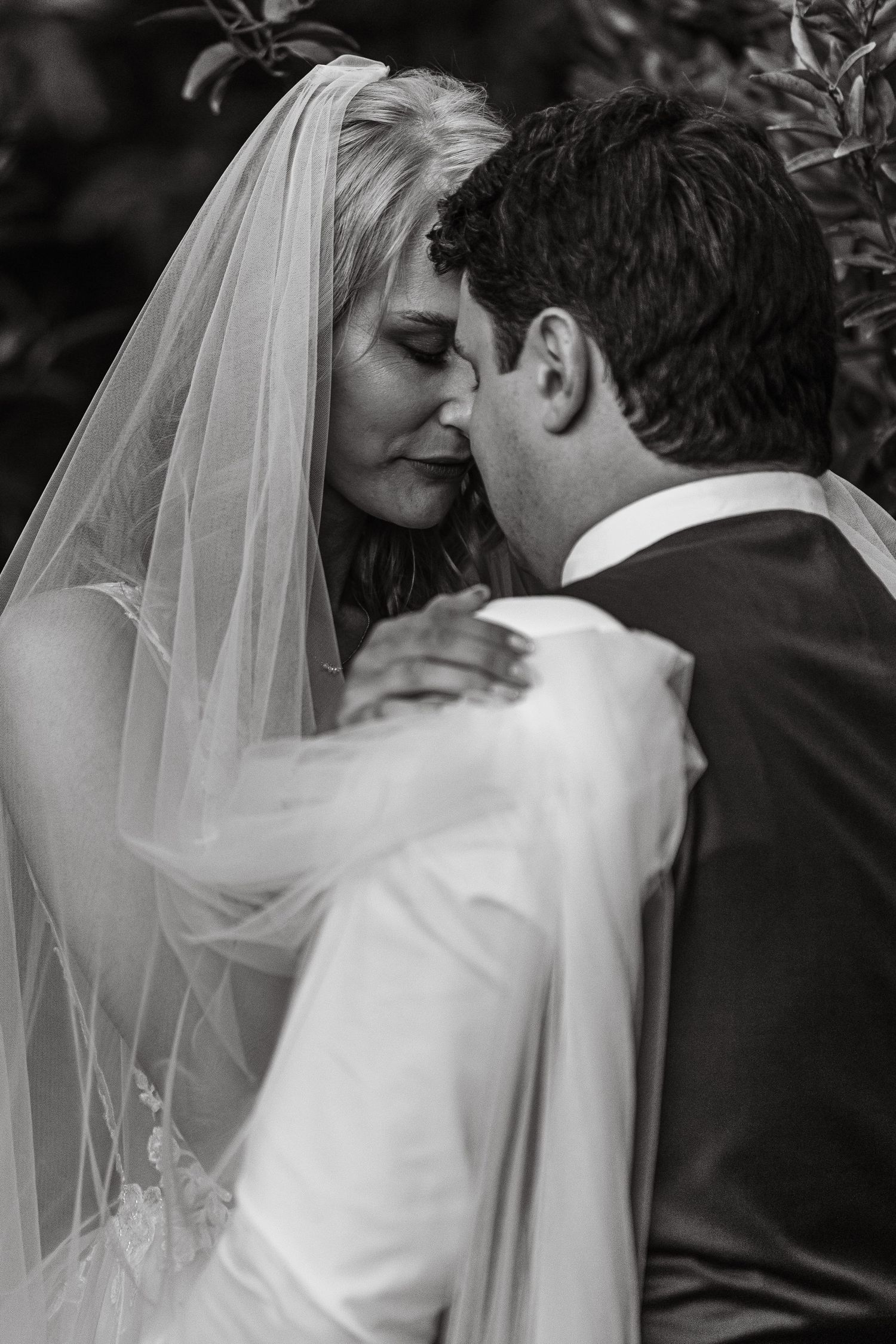 An intimate black and white wedding portrait capturing a tender moment between newlyweds.