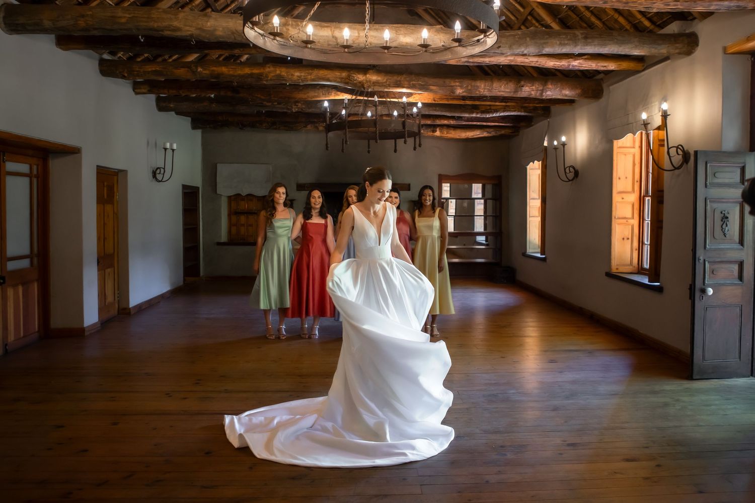 Rustic wedding venue interior with exposed wooden beams and elegant chandelier lighting.