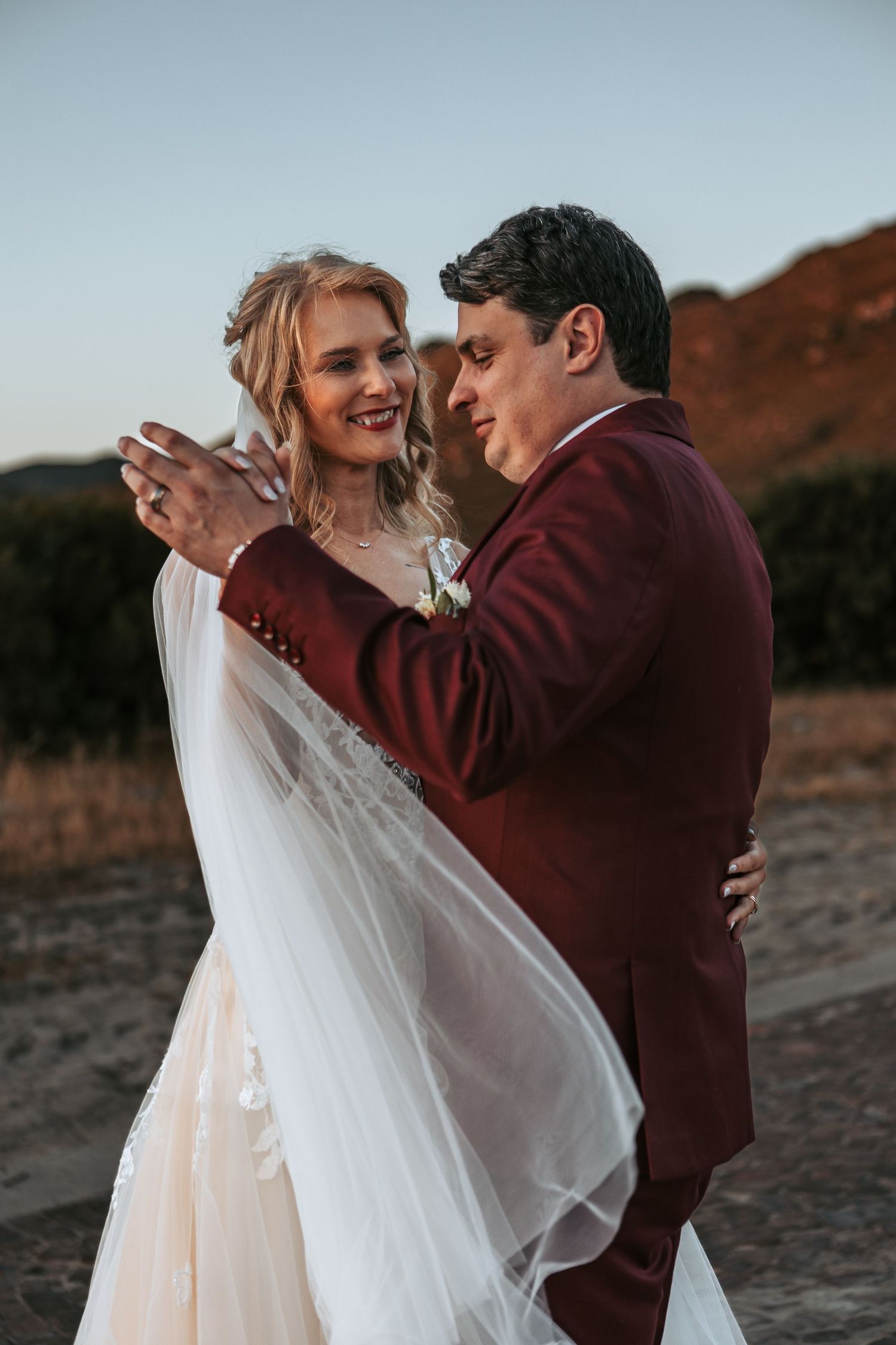 A tender moment between newlyweds during their sunset desert photo session.