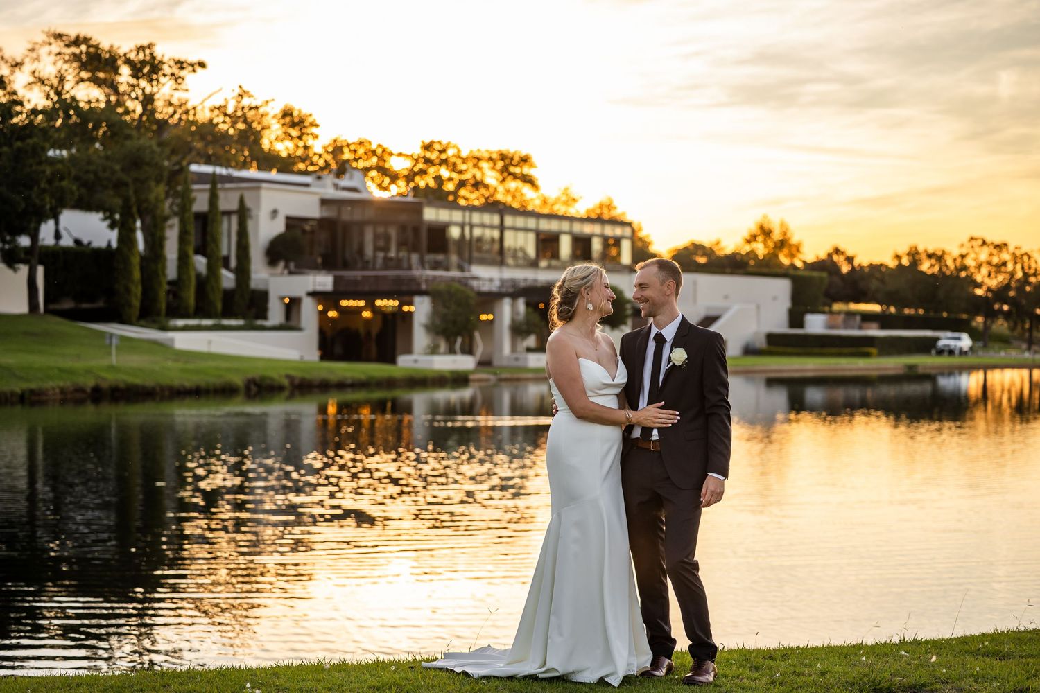 Romantic sunset wedding photos by a lake with golden light reflecting on the water.