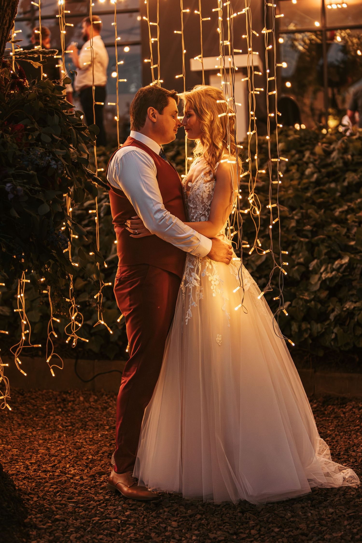 Romantic wedding portrait with cascading string lights creating a warm evening glow.