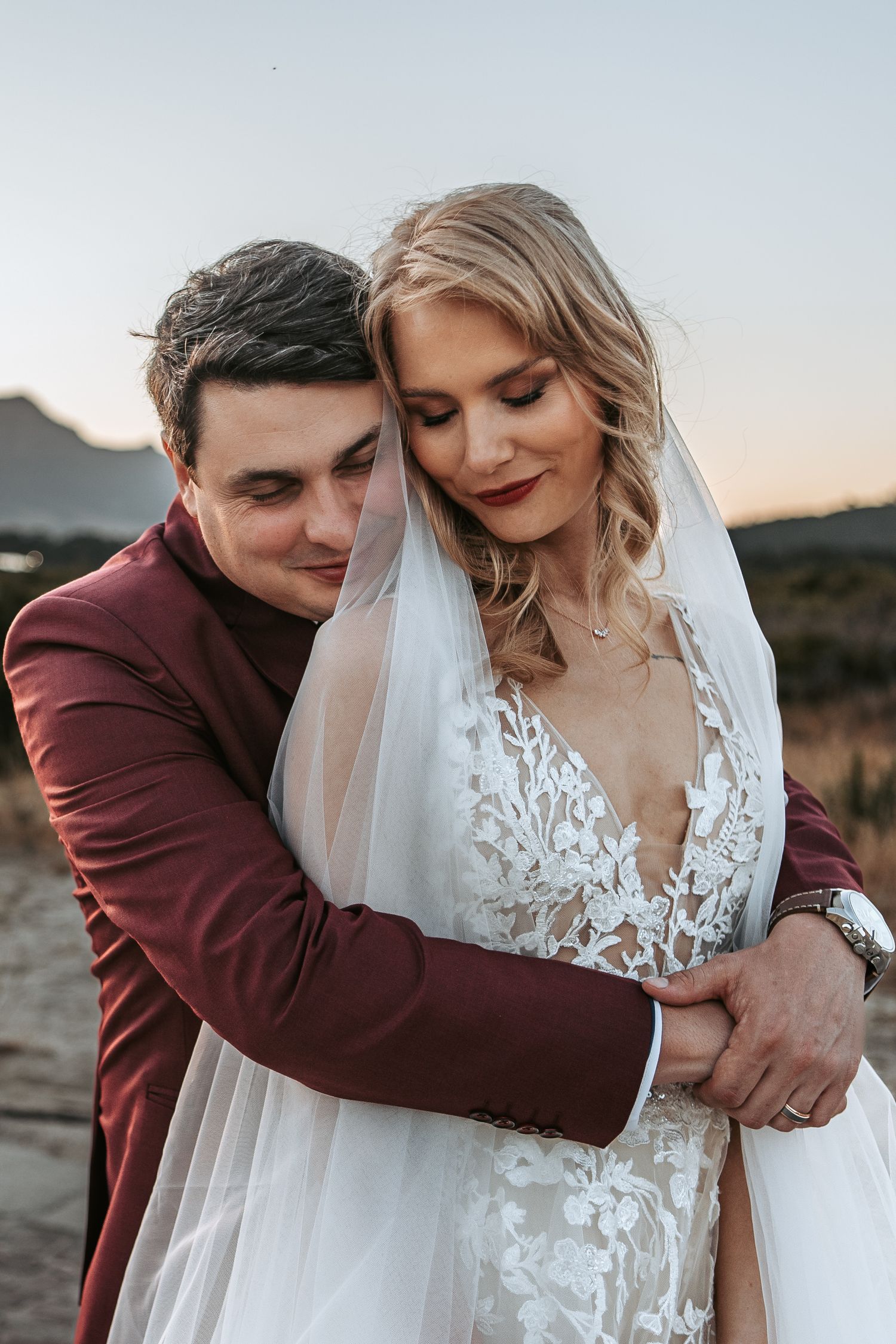 Close-up wedding portrait showing intimate moment against mountain backdrop.