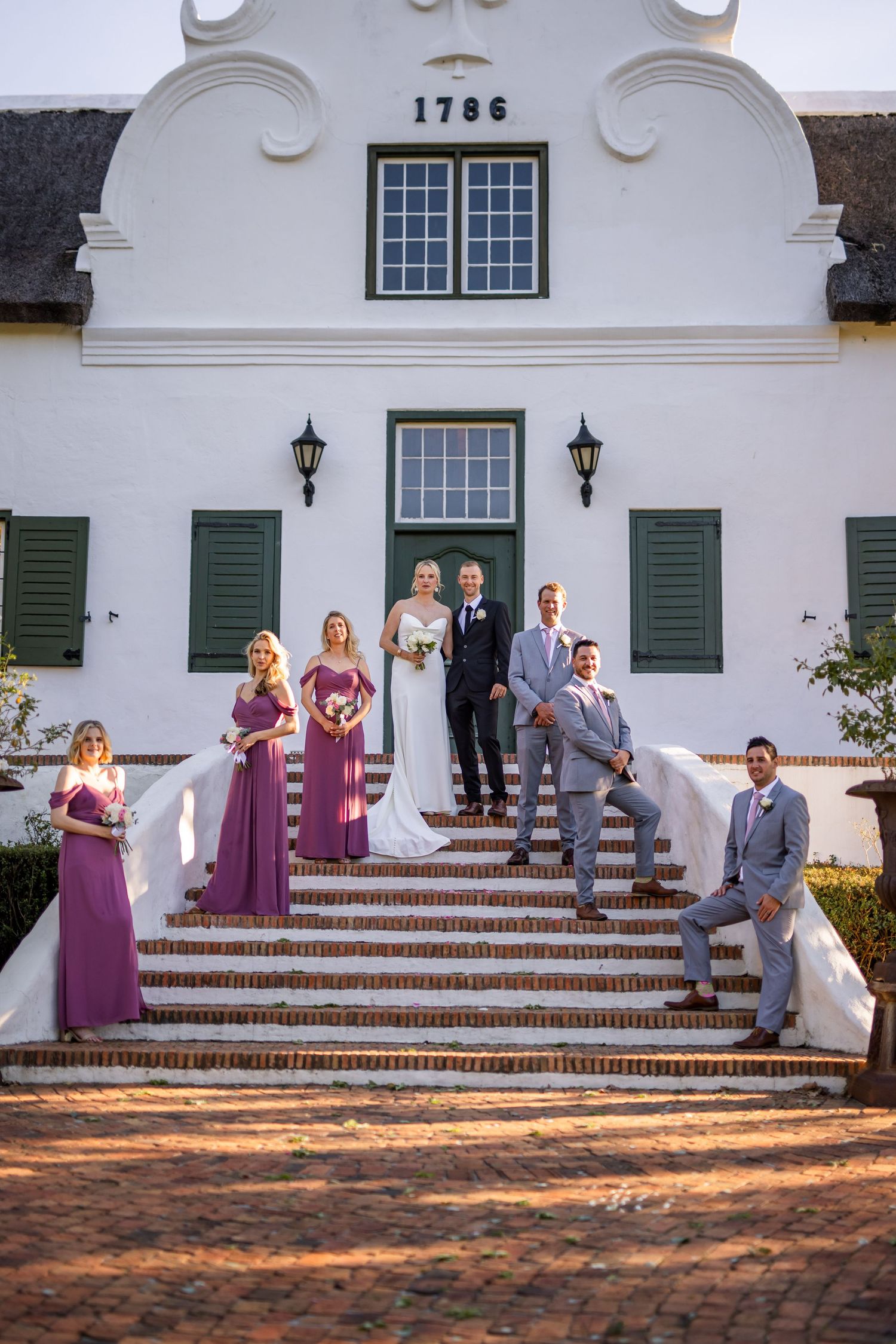 Wedding party poses on steps of a historic white colonial building dated 1786.